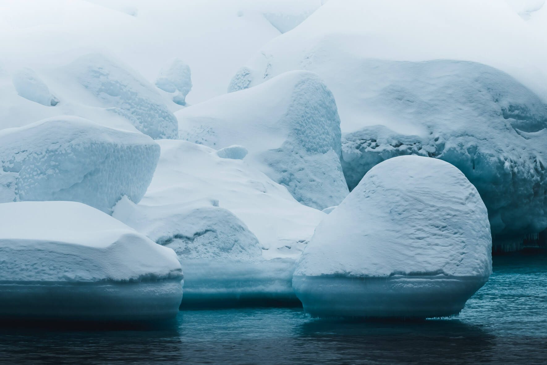 Blue water and white snow over icebergs in Greenland