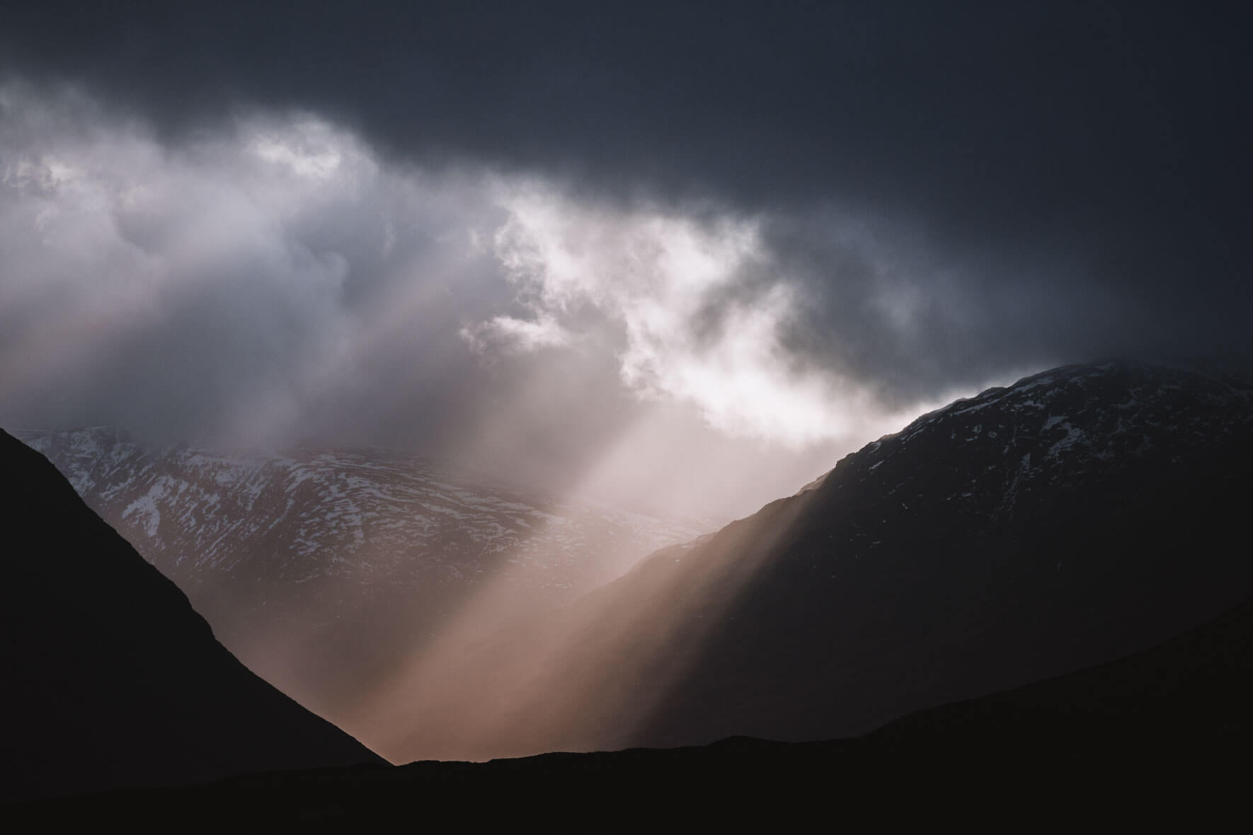 Sun breaking through the dark clouds over Glen Etive in Scotland