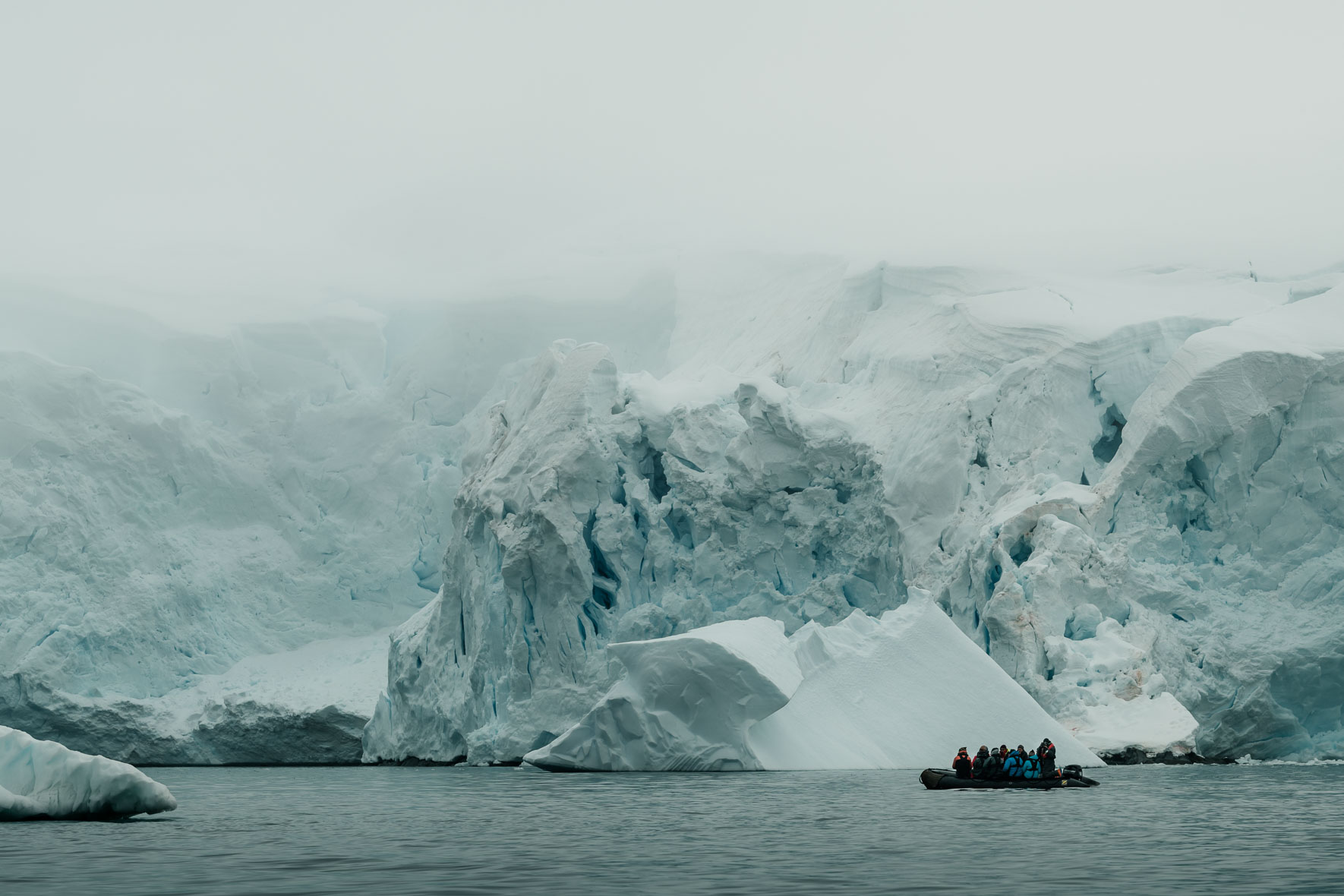 Zodiac between icebergs and glaciers in Antarctica