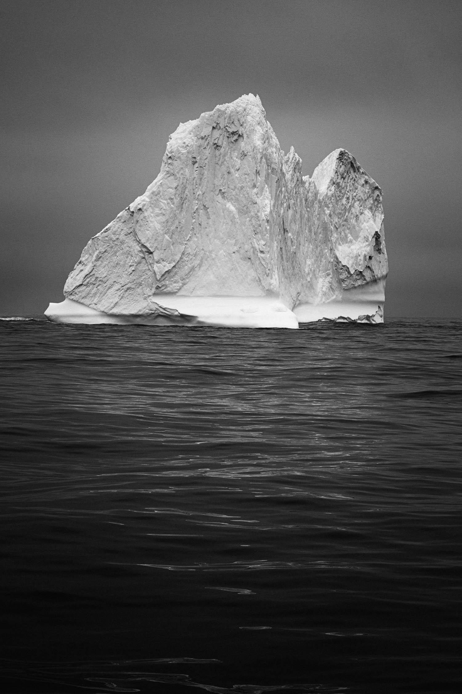 Black and white photo of iceberg with reflections in the water