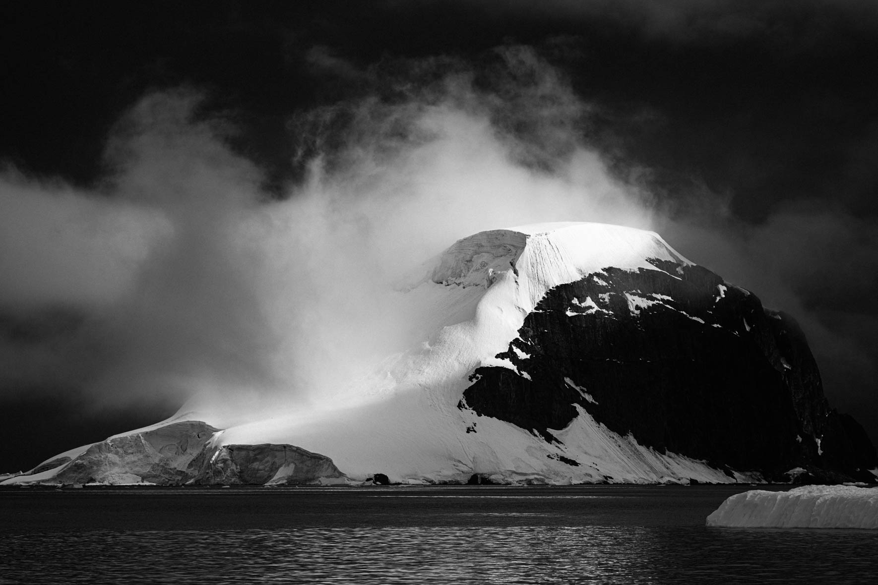 Black and white photo of mountain in the clouds in Antarctica