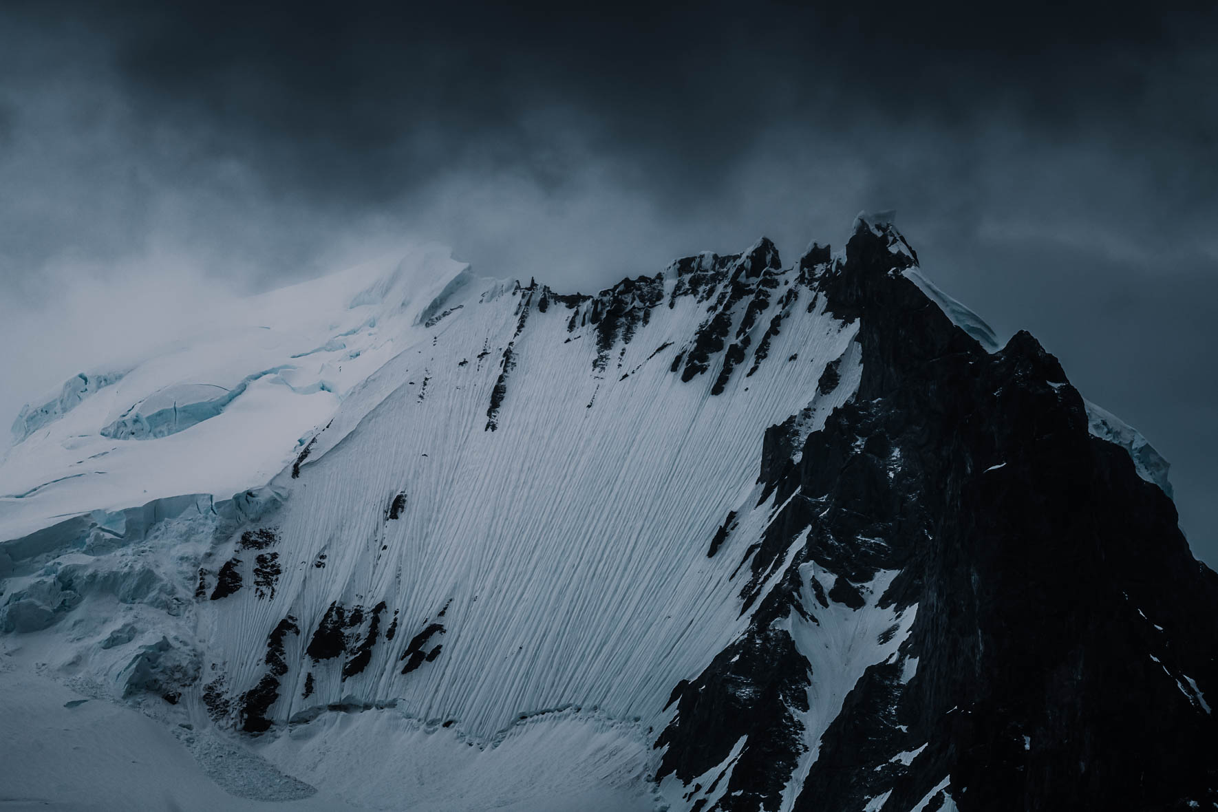 Dark clouds over snowy mountain with glacier in Antarctica
