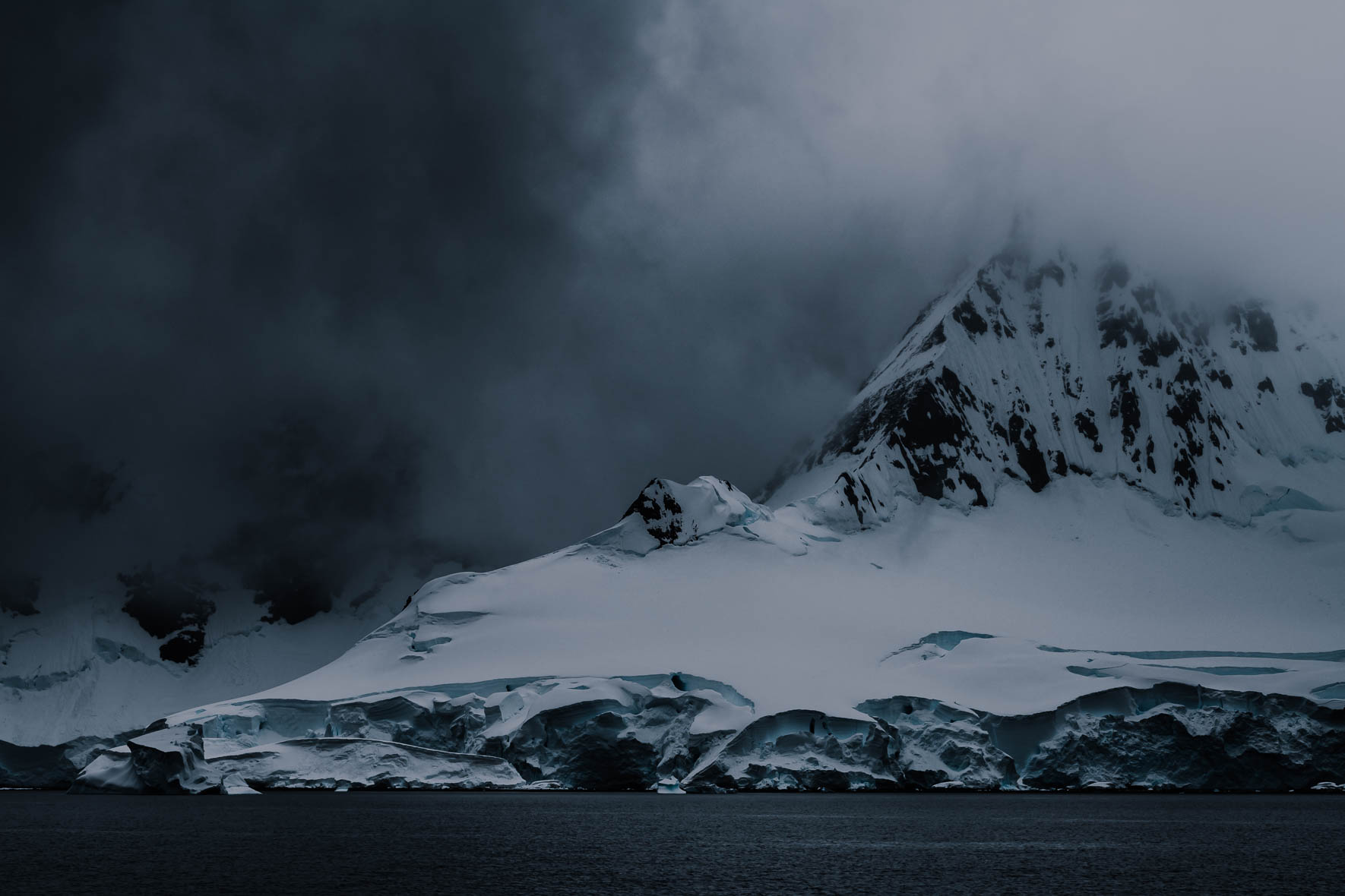 Dark clouds over snowy mountain with glacier in Antarctica