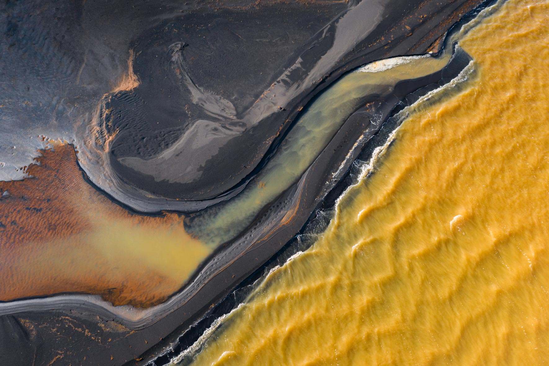 Abstract yellow lake with dark shoreline and small waves in Iceland