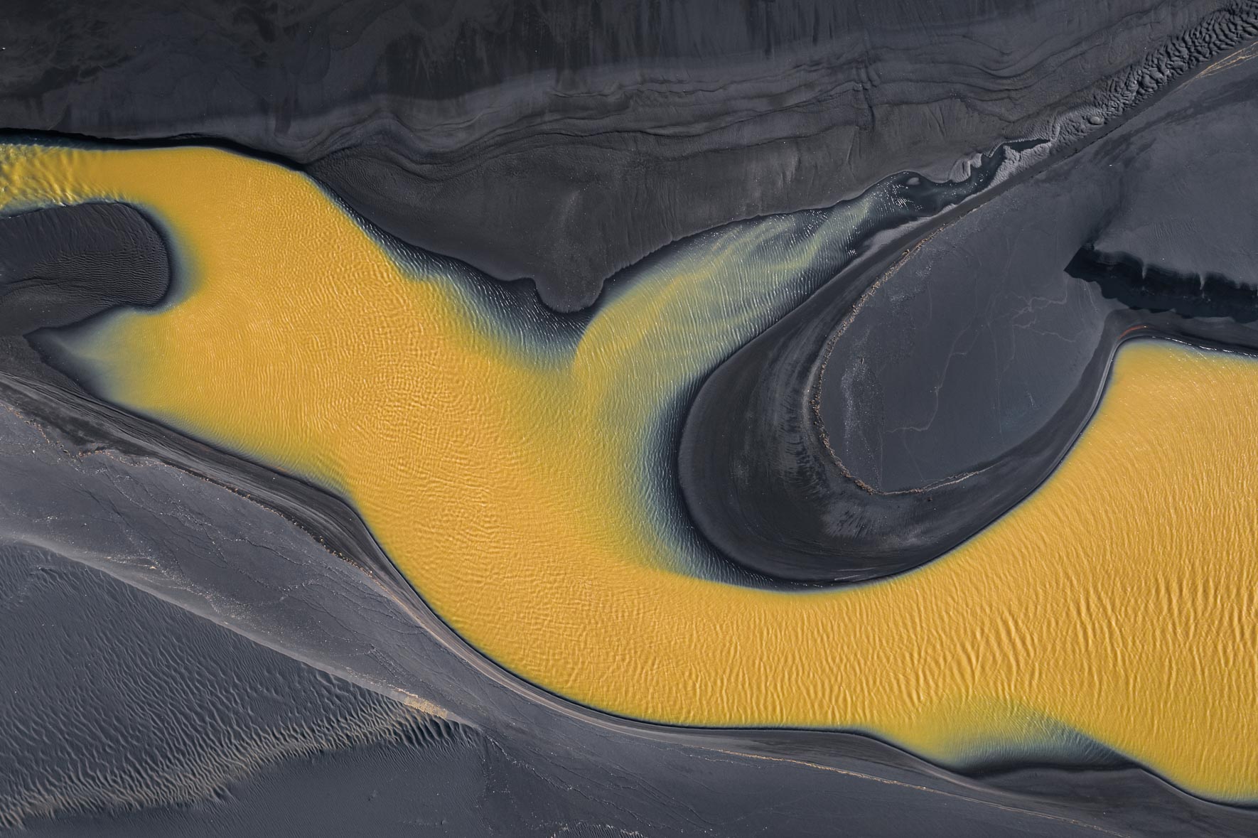 Aerial photograph of yellow river in Iceland with black sand