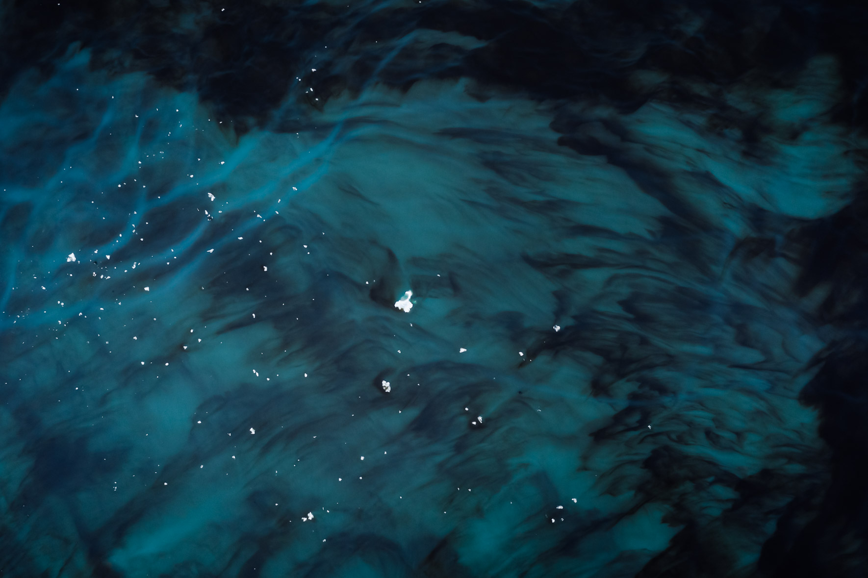 Aerial photography of small icebergs floating in a dark blue lake