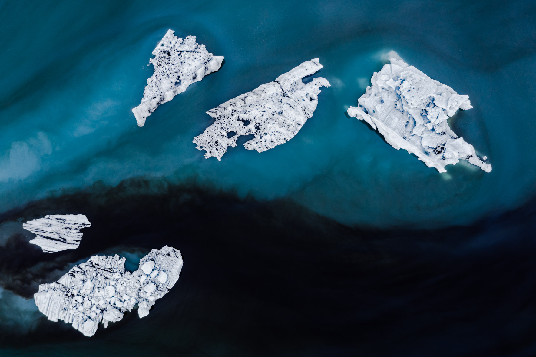 Aerial photography of icebergs in dark blue and black water