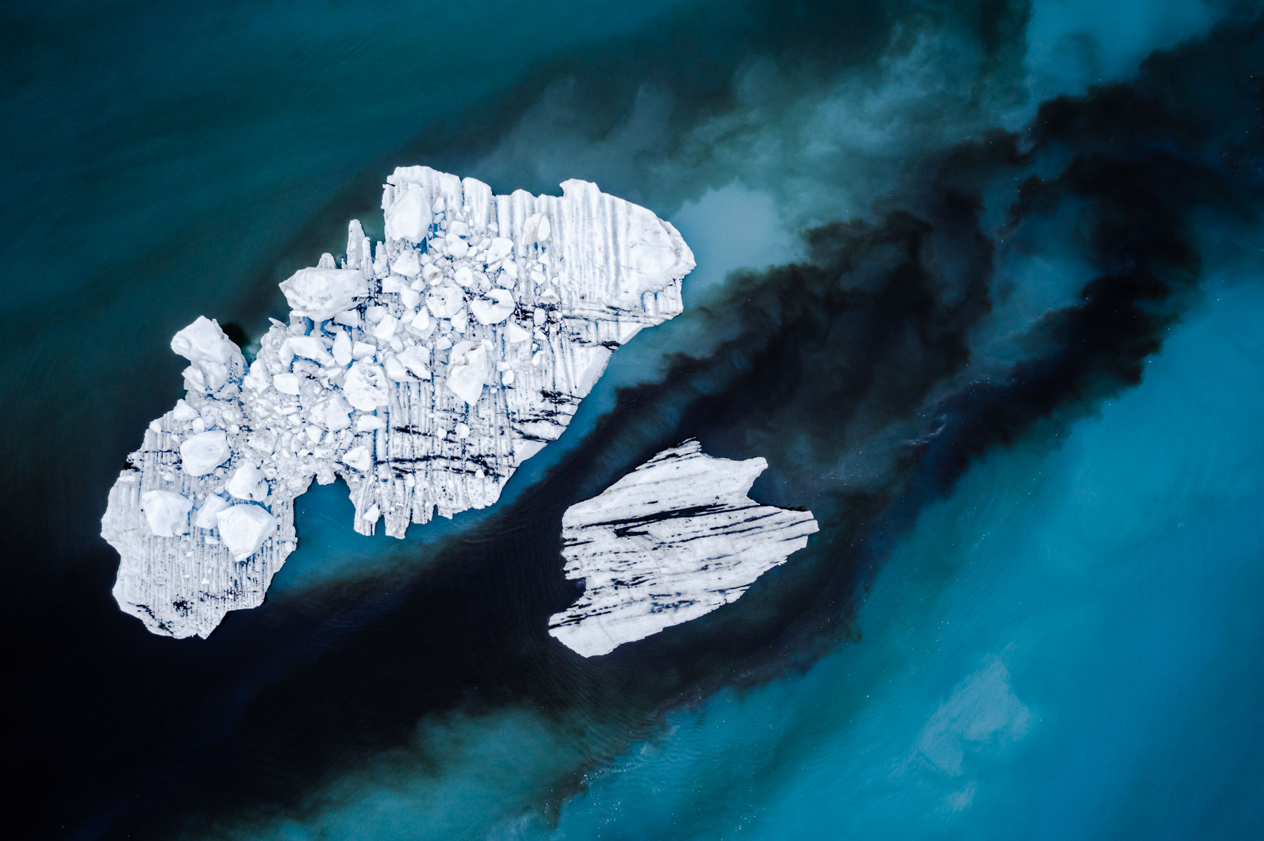 Aerial photography of icebergs in dark blue and black water