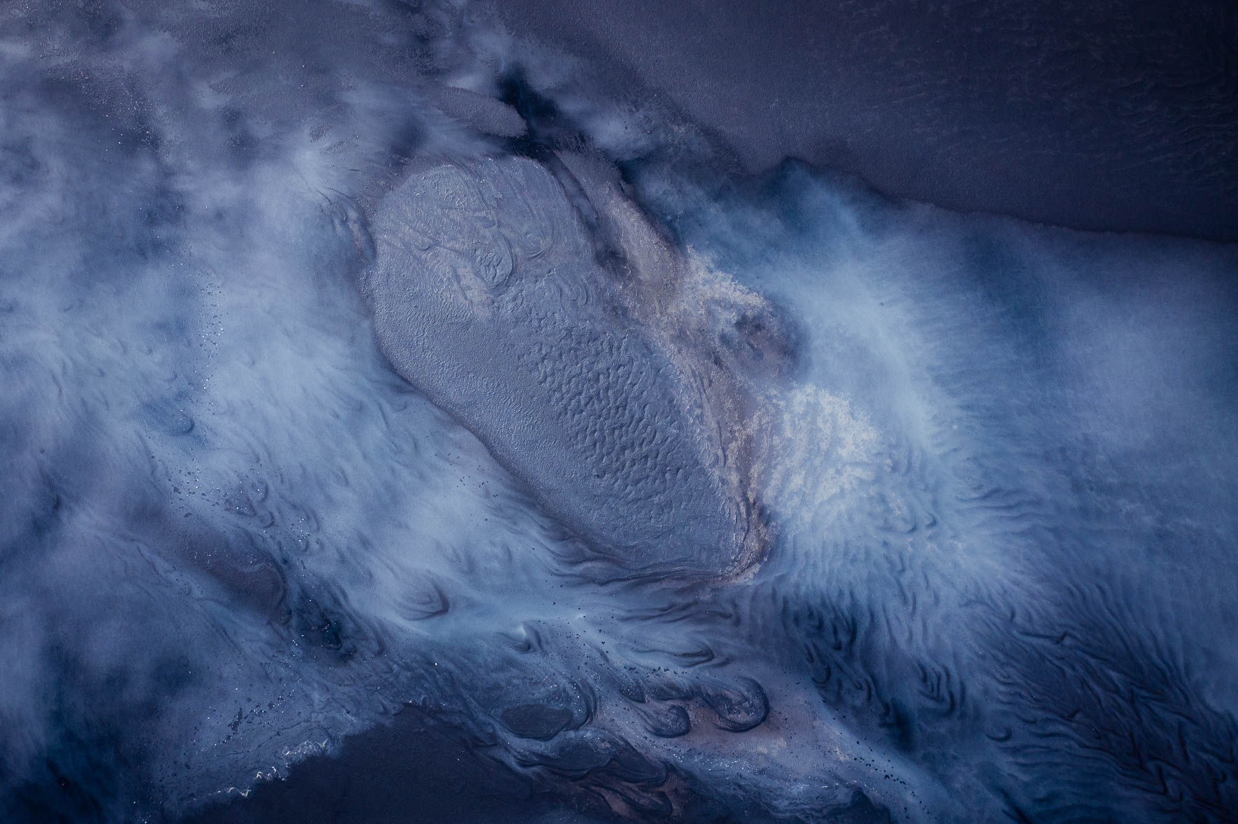 Aerial View of Abstract Tidal Patterns with Black Sand and Blue Water
