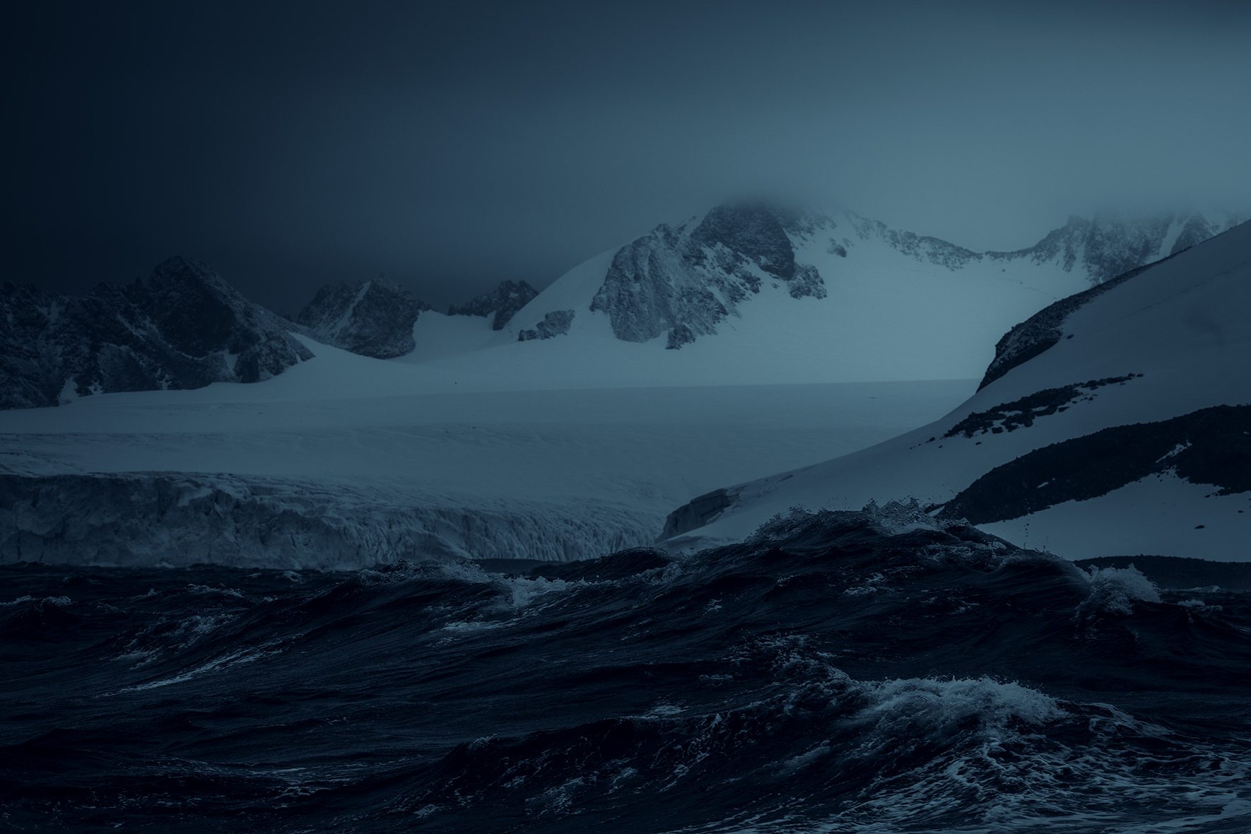 Dark glacier landscape with ocean and waves