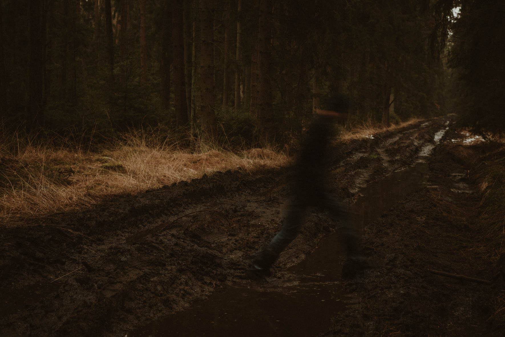 Man jumping over puddle in dark forest