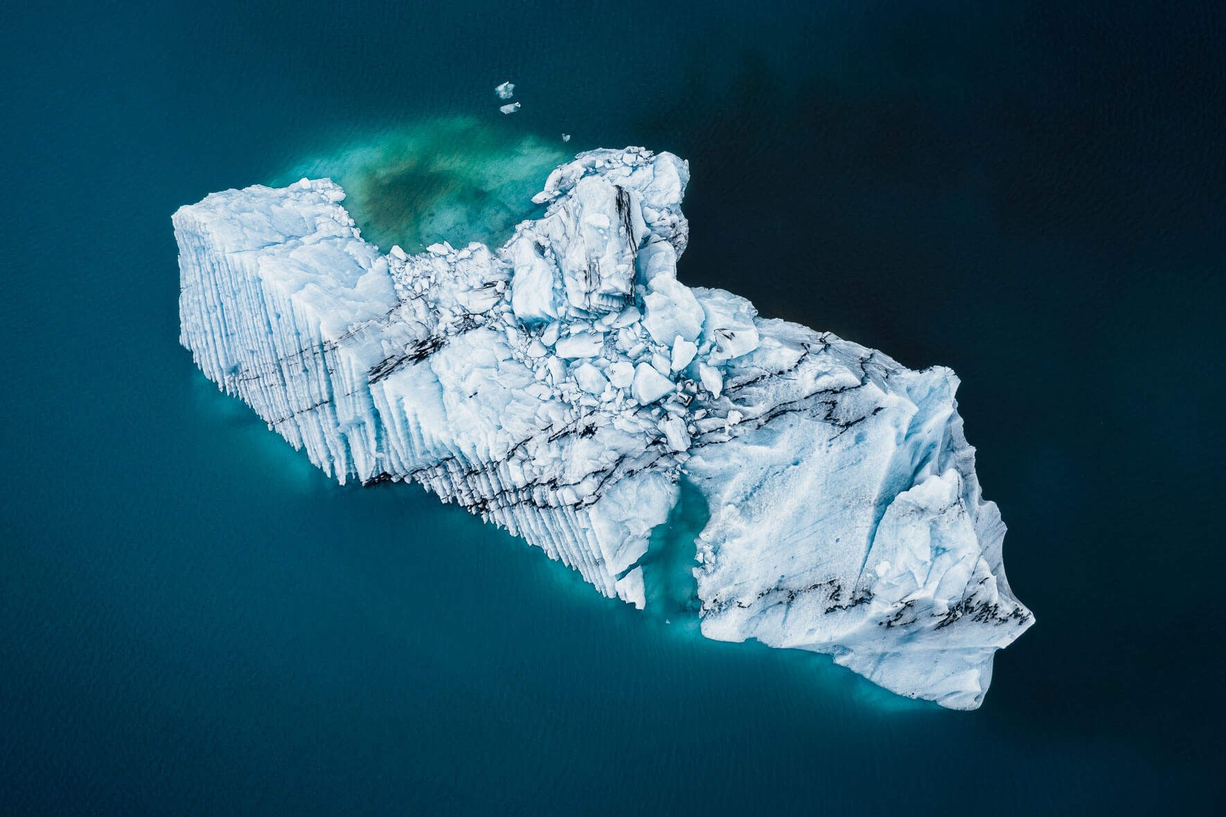 Aerial photography of icebergs with ash in turquoise glacier lagoon in Iceland