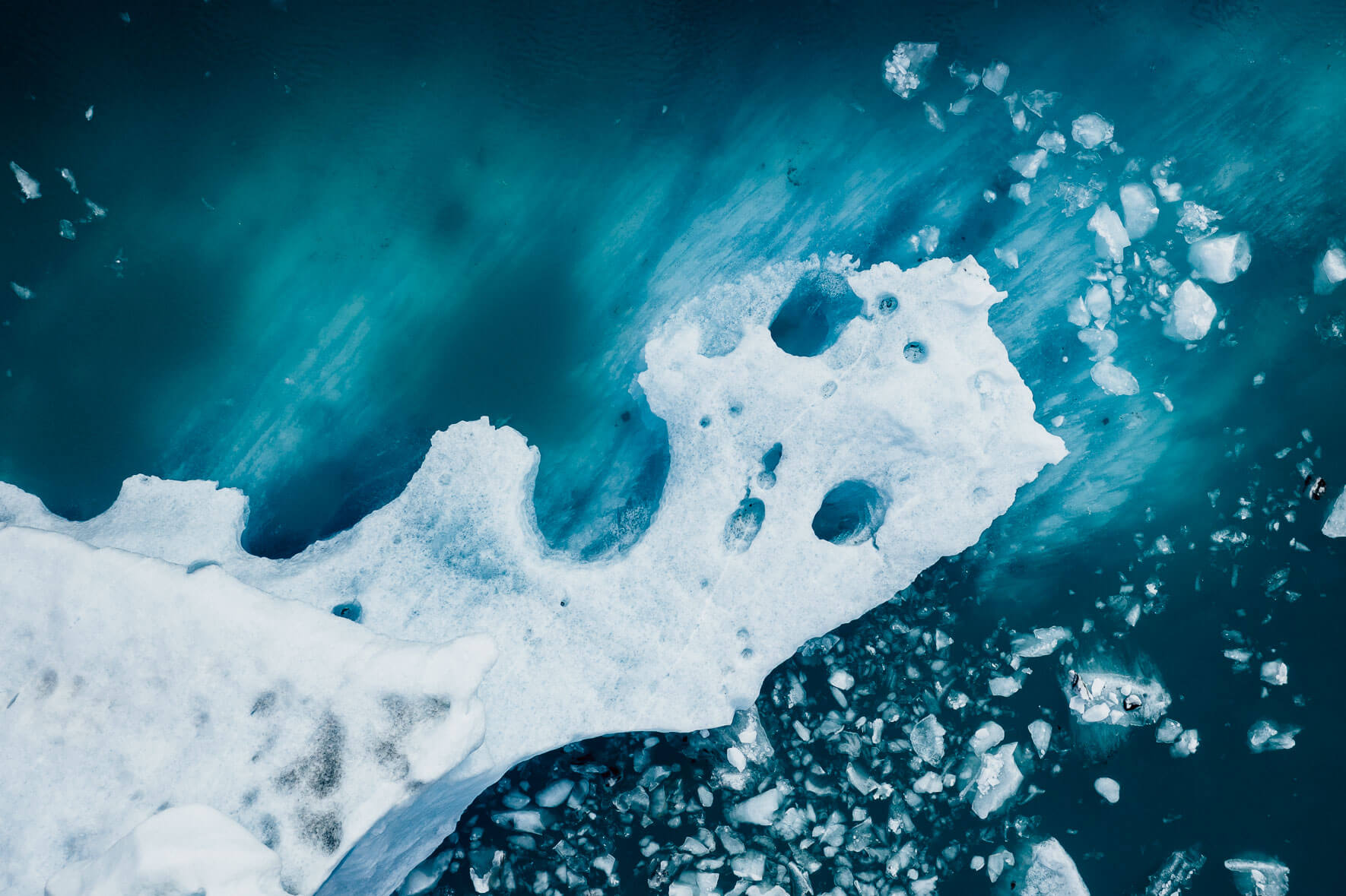 Abstract aerial photograph of icebergs with ash in turquoise glacier lagoon in Iceland