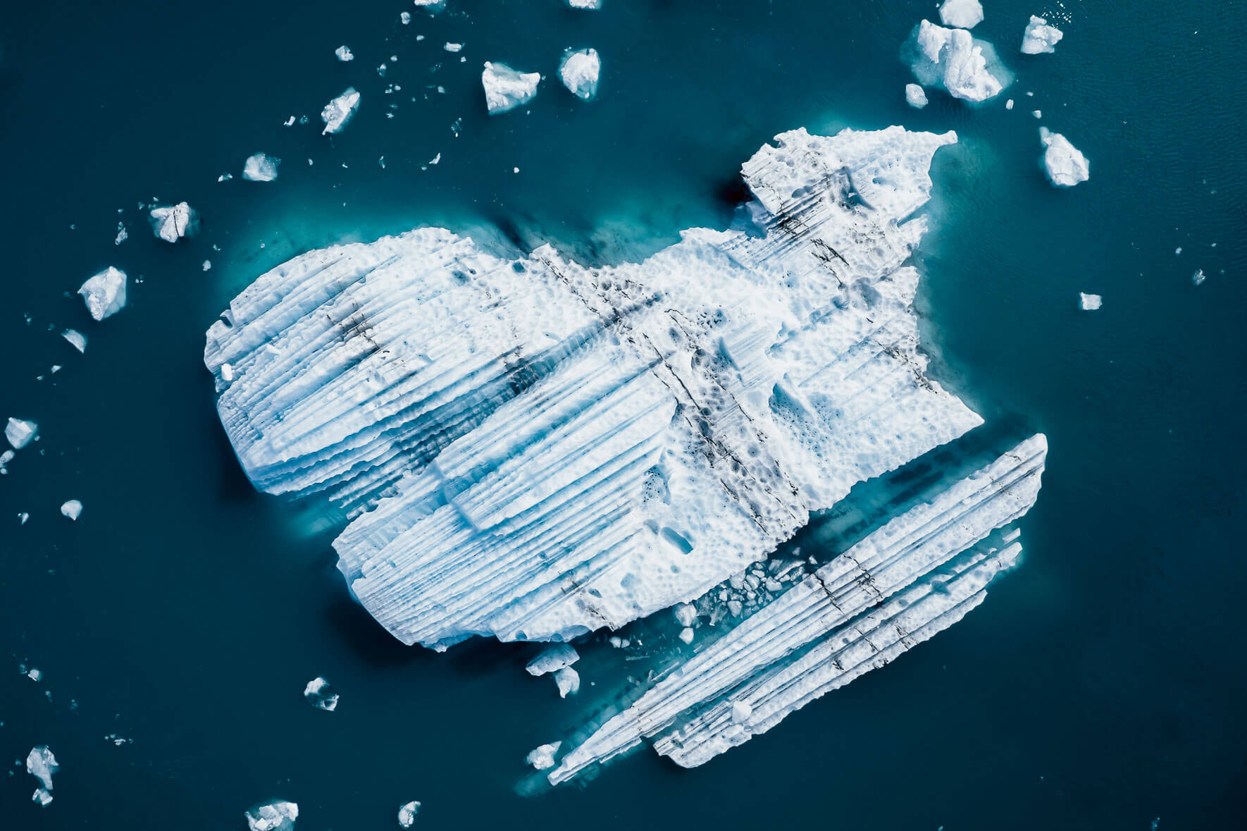 Aerial photography of icebergs with ash in turquoise glacier lagoon in Iceland