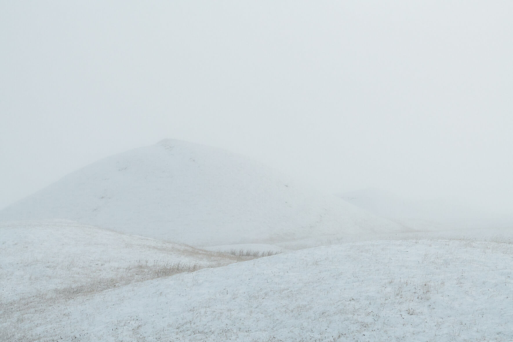 Minimalist scene with snow covered hill in winter fog