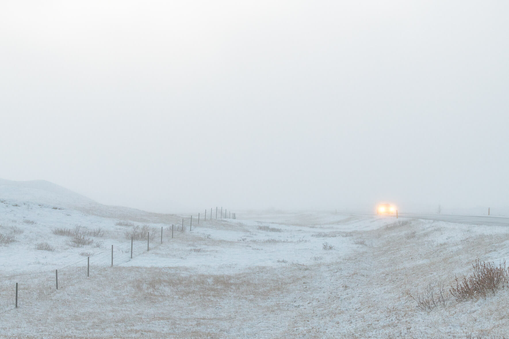 Snow covered road with car in fog