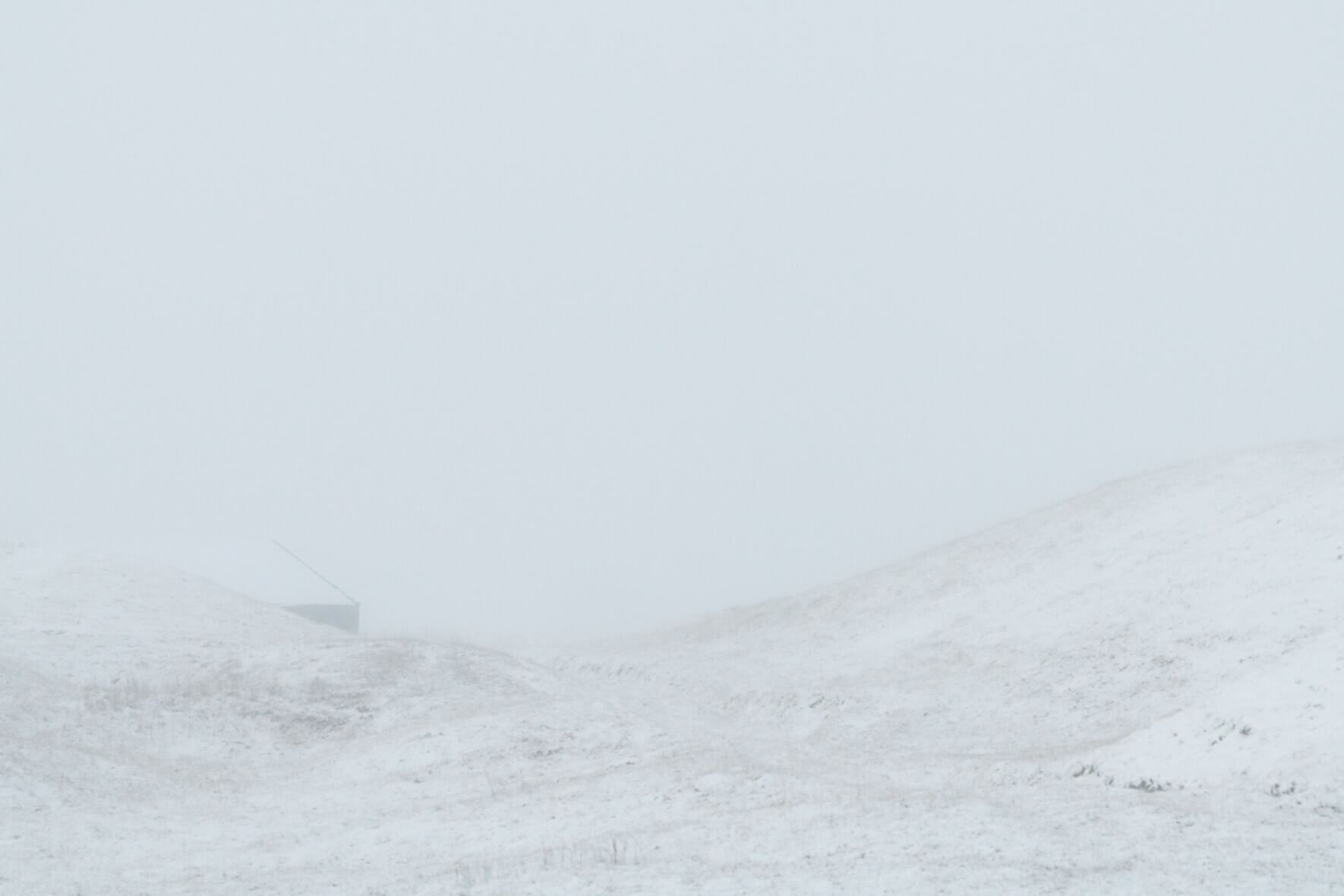 Minimalist scene with snow covered hill and house in fog