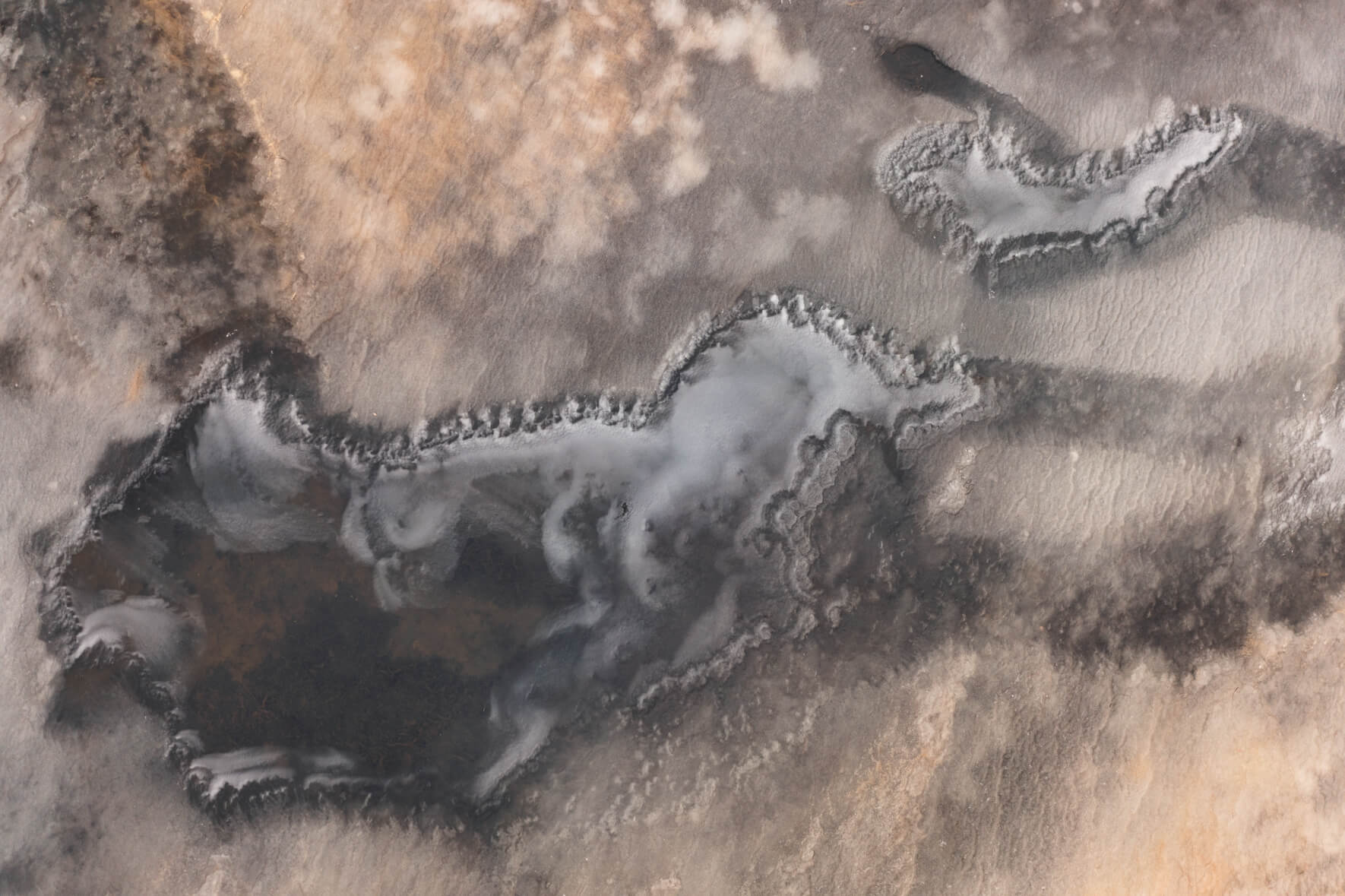 Abstract aerial photograph of frozen pond with ice and sand in eastern Iceland