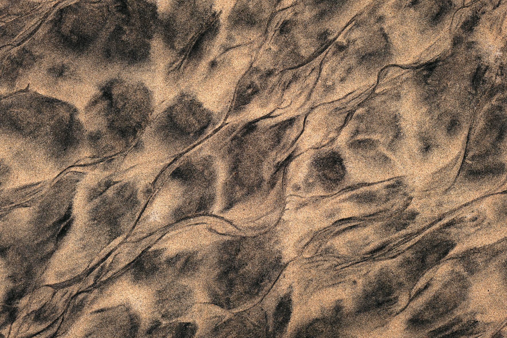 Abstract shapes in sand drawn by sea water in the Westfjords of Iceland