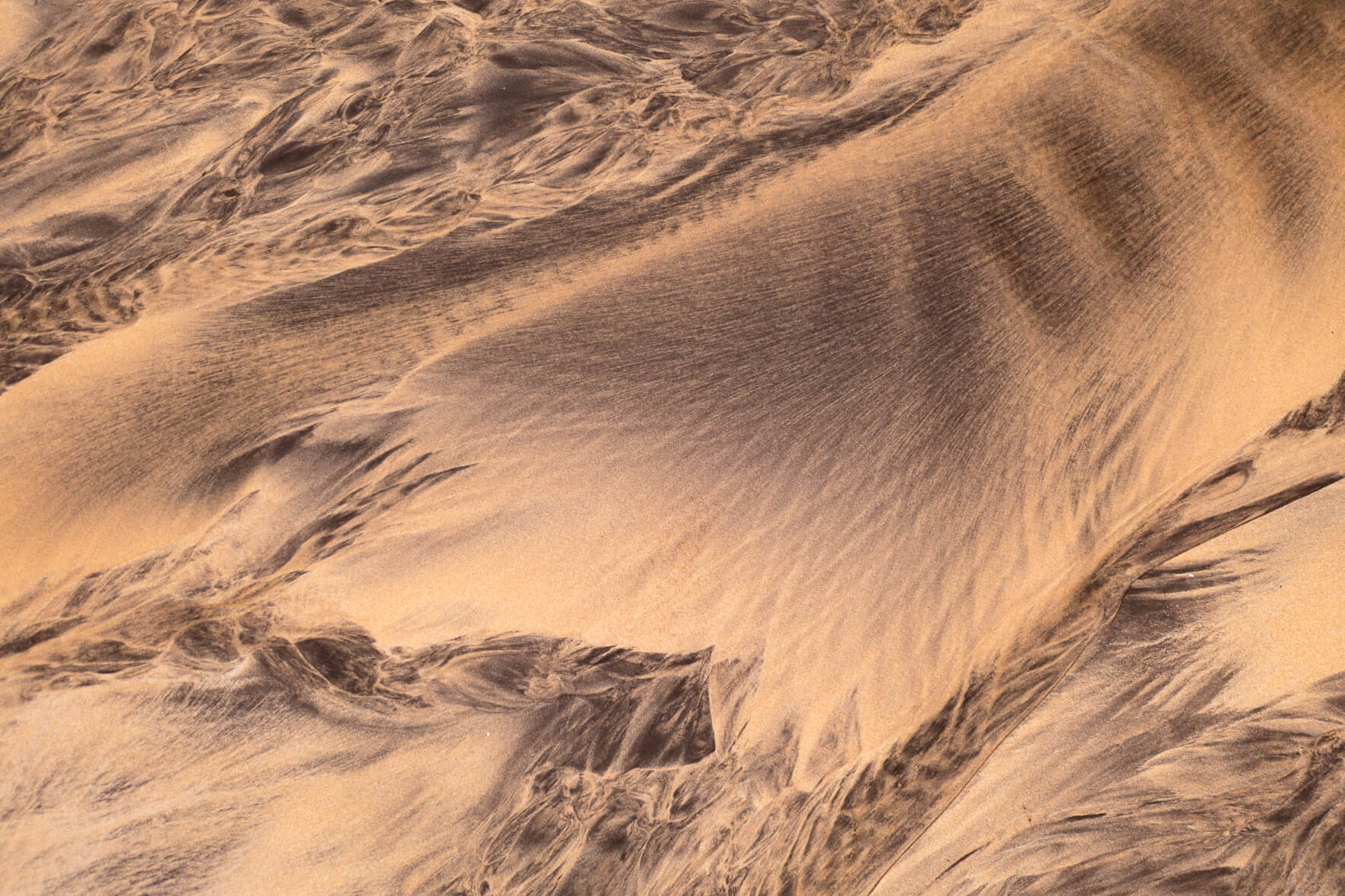 Aerial view of a creek running over the beach into the ocean