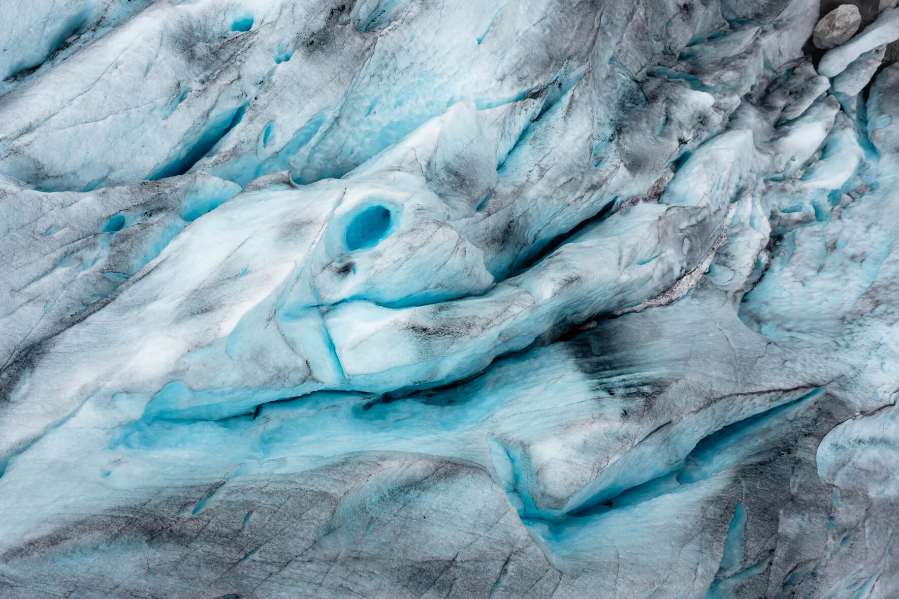 Aerial view of deep crevasses on a glacier in Norway with dark sand and sediment
