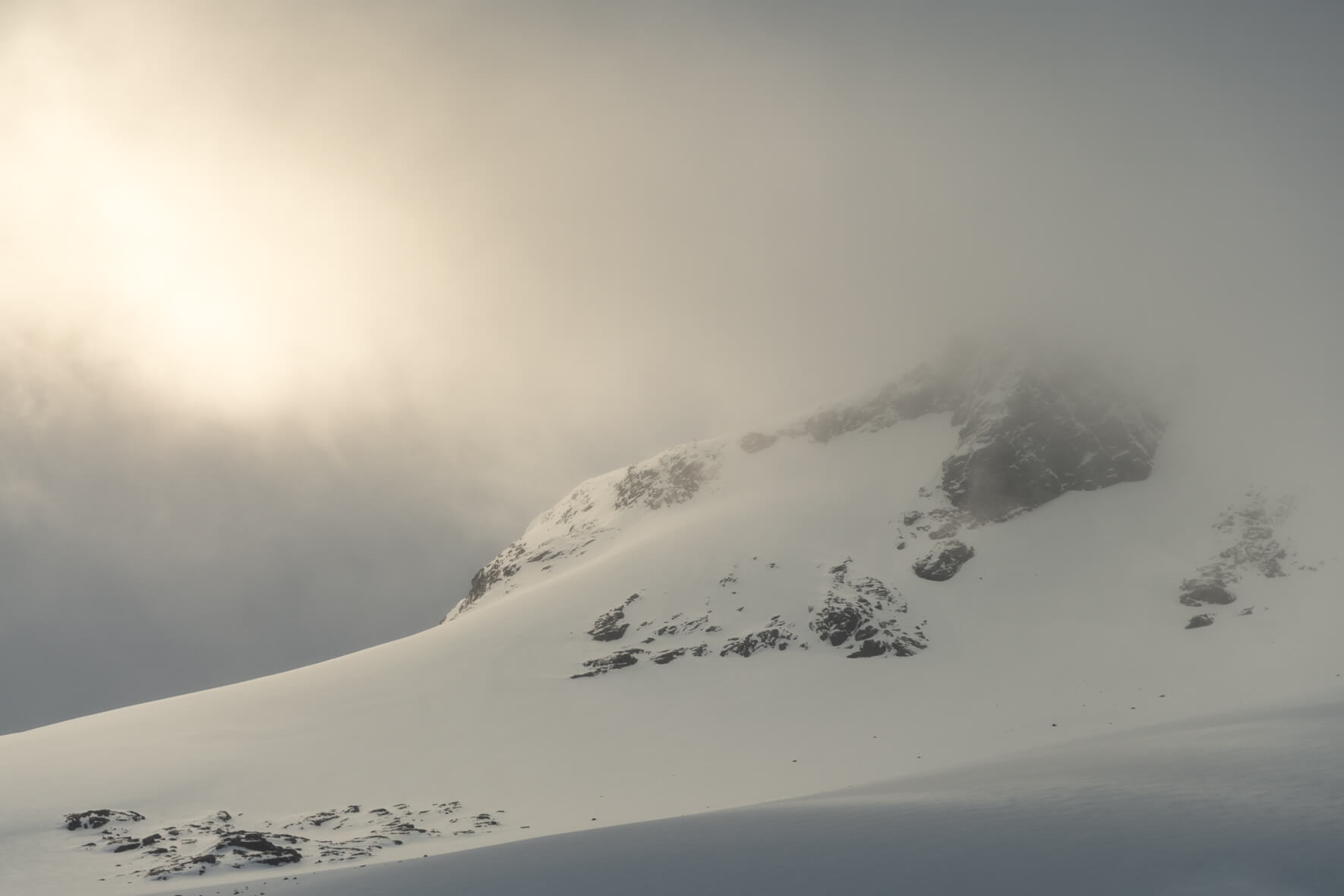 Sun breaks through the clouds over the Sognefjellet mountains and snow-capped peaks in Norway