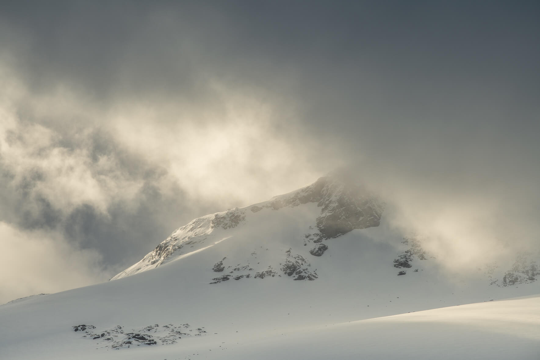 Sun breaks through the dark clouds over the Sognefjellet mountains in Norway in winter