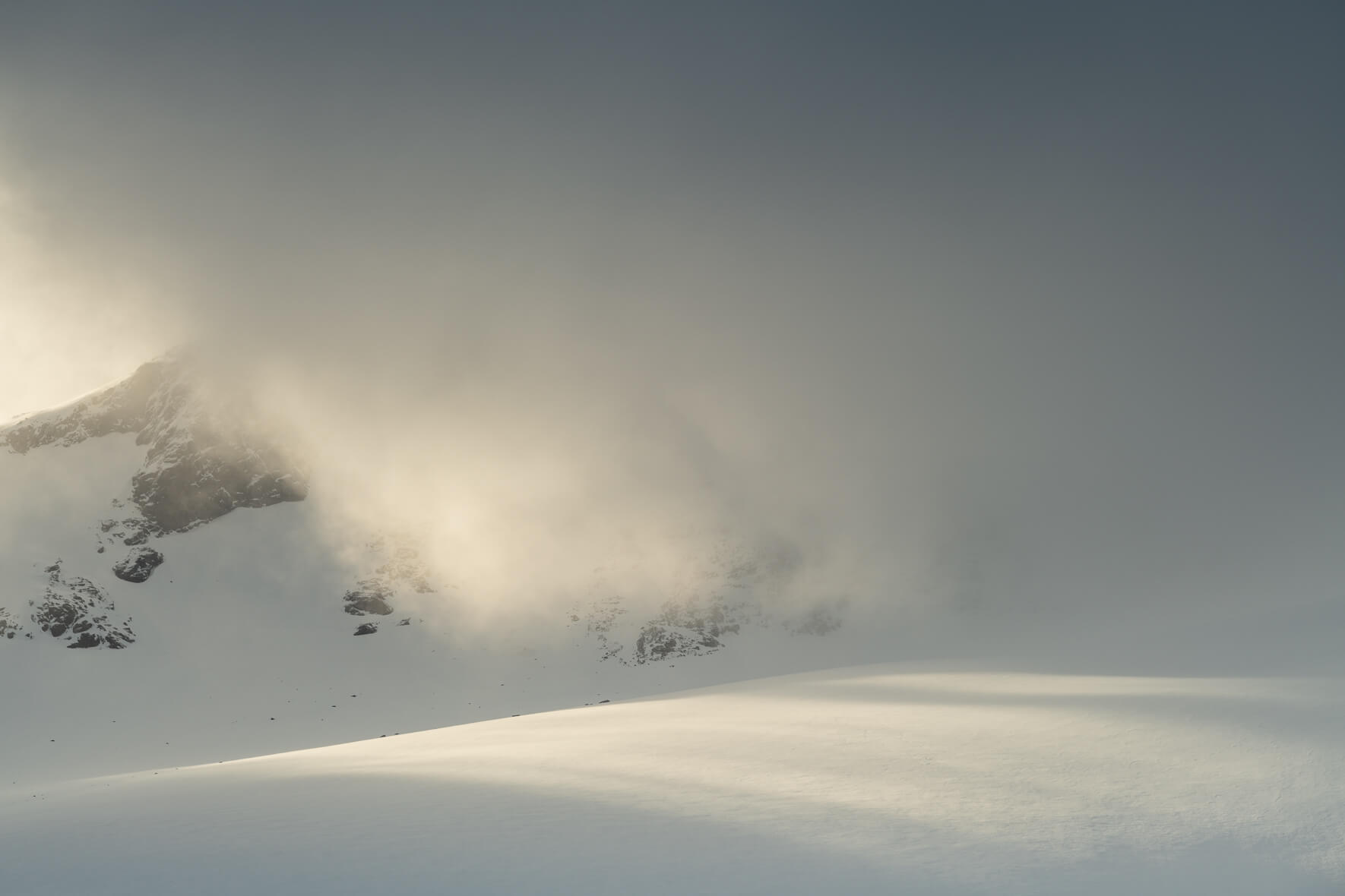 Sun breaks through the clouds over the Sognefjellet mountains and snow covered glacier
