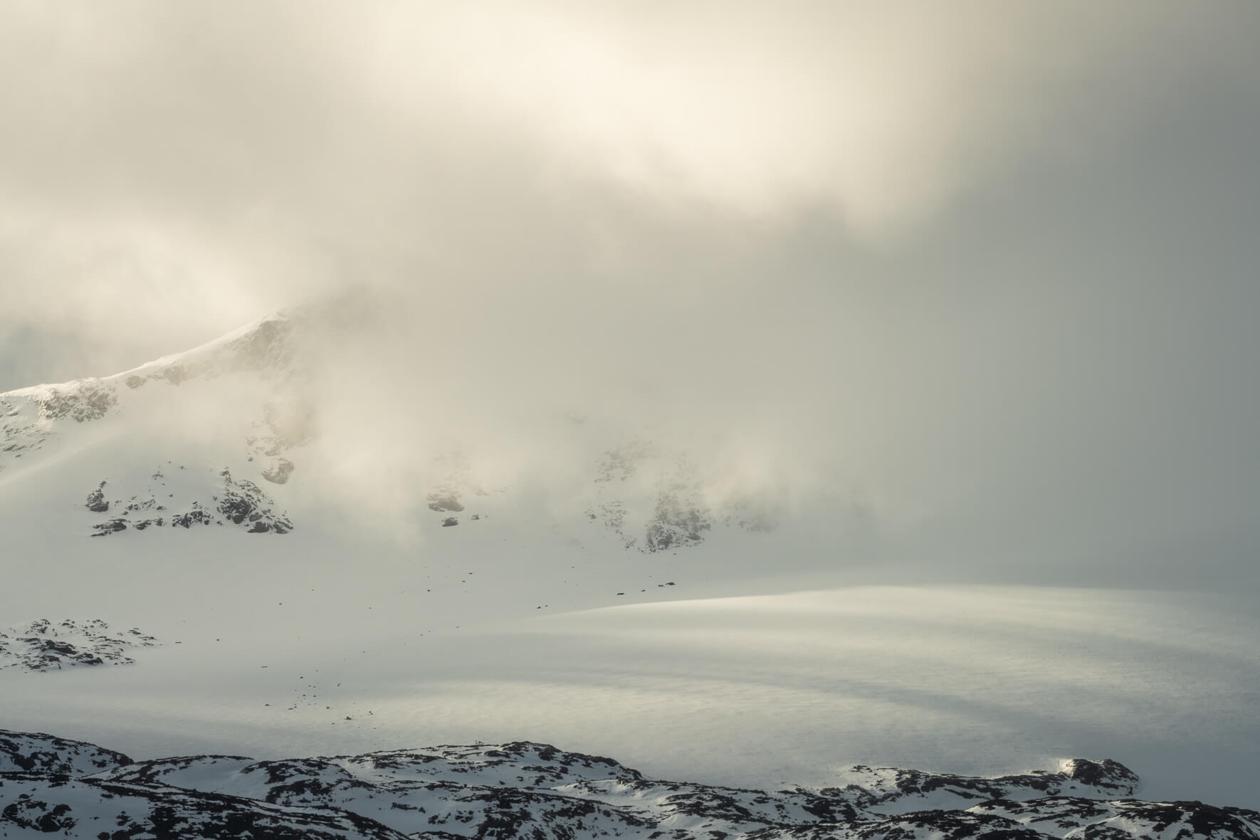 The sun breaks through the clouds over the Sognefjellet mountains with dramatic and warm light