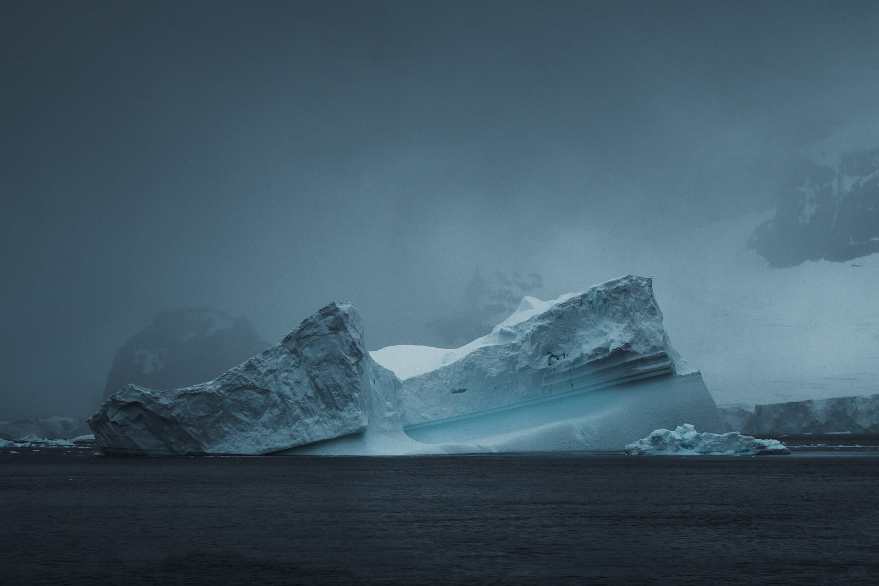 Majestic iceberg surrounded by ominous skies and mountains in Antarctica
