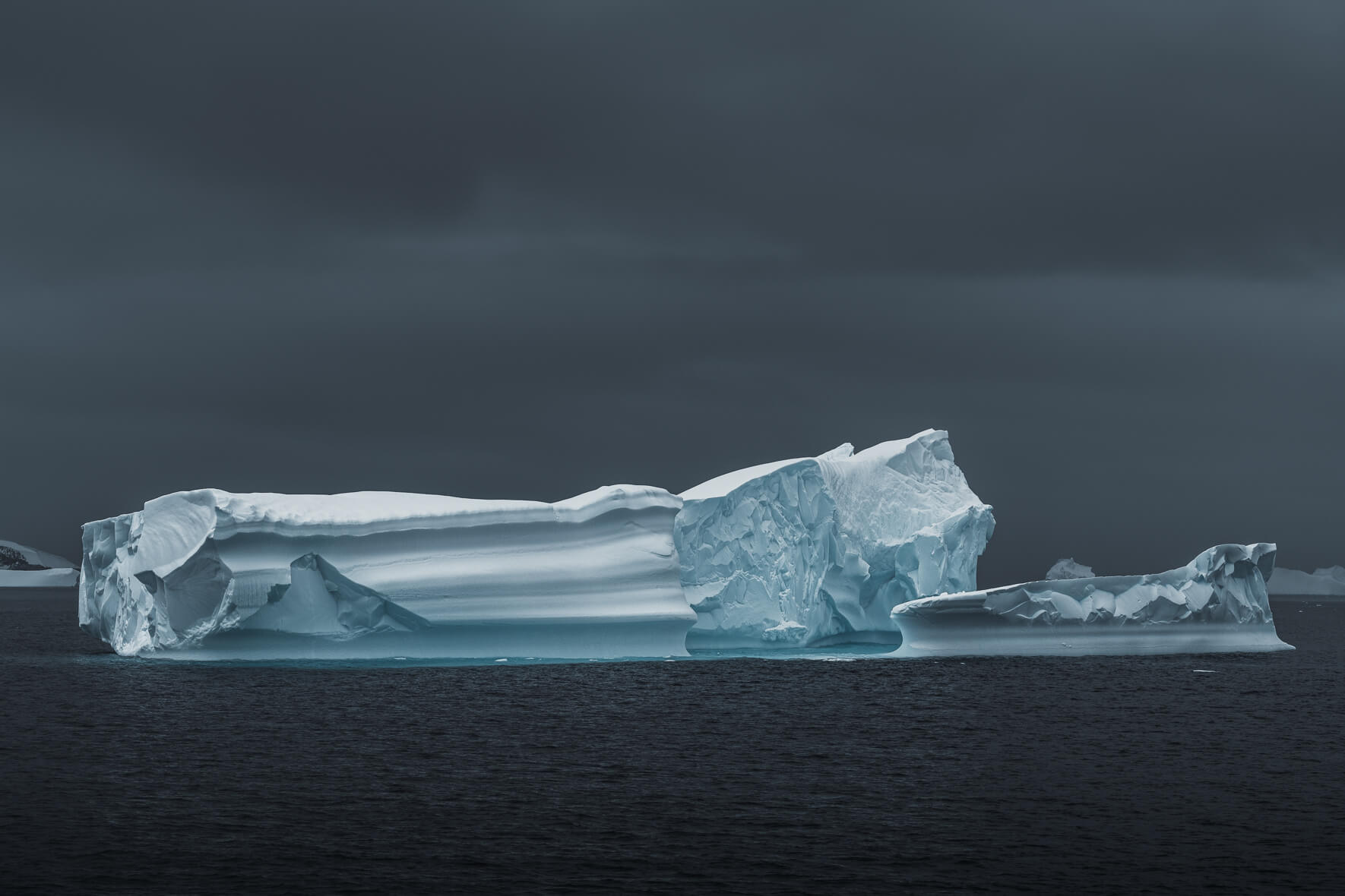 A group of large icebergs under dark skies in Antarctica