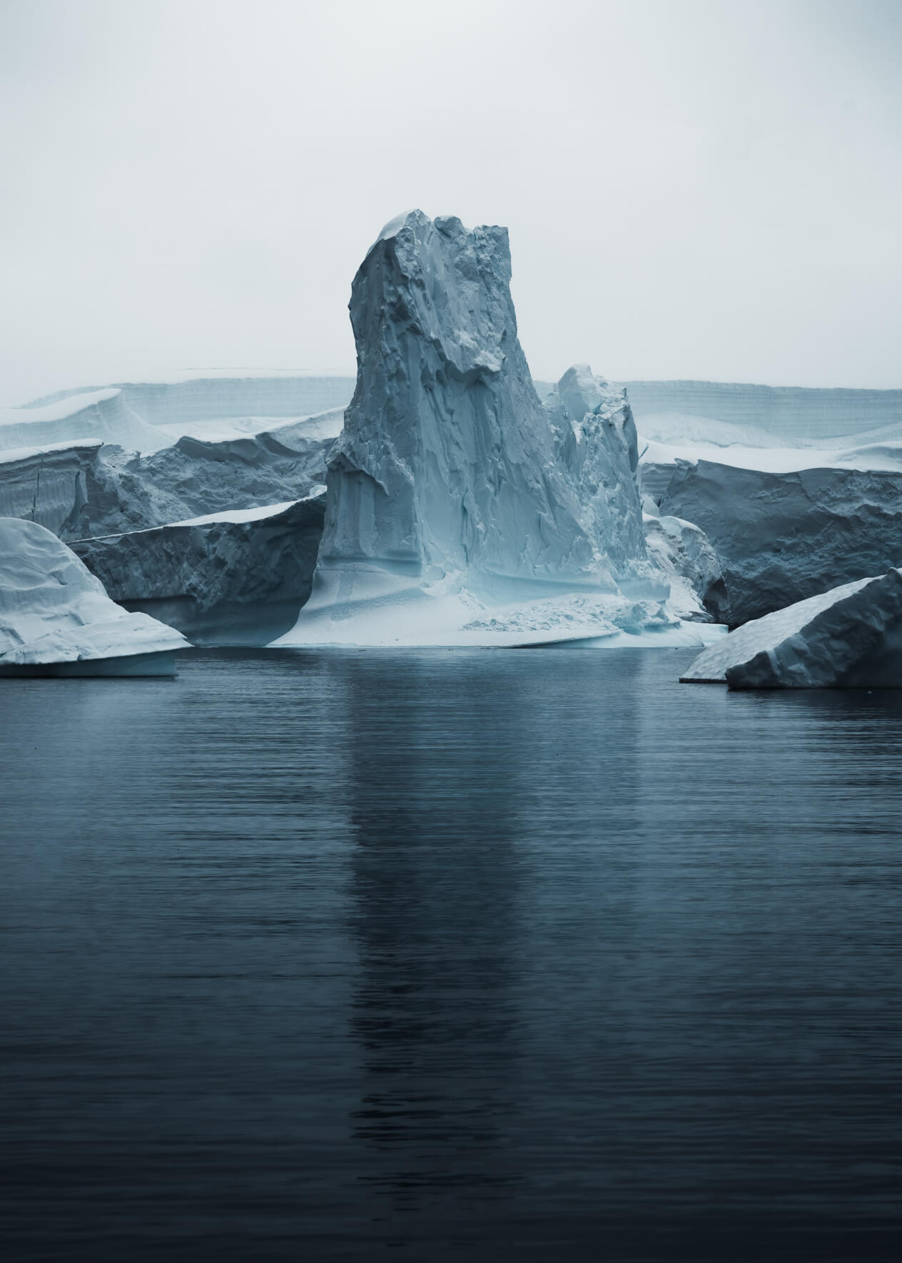 Towering iceberg in dark ocean with magical reflections in Antarctica