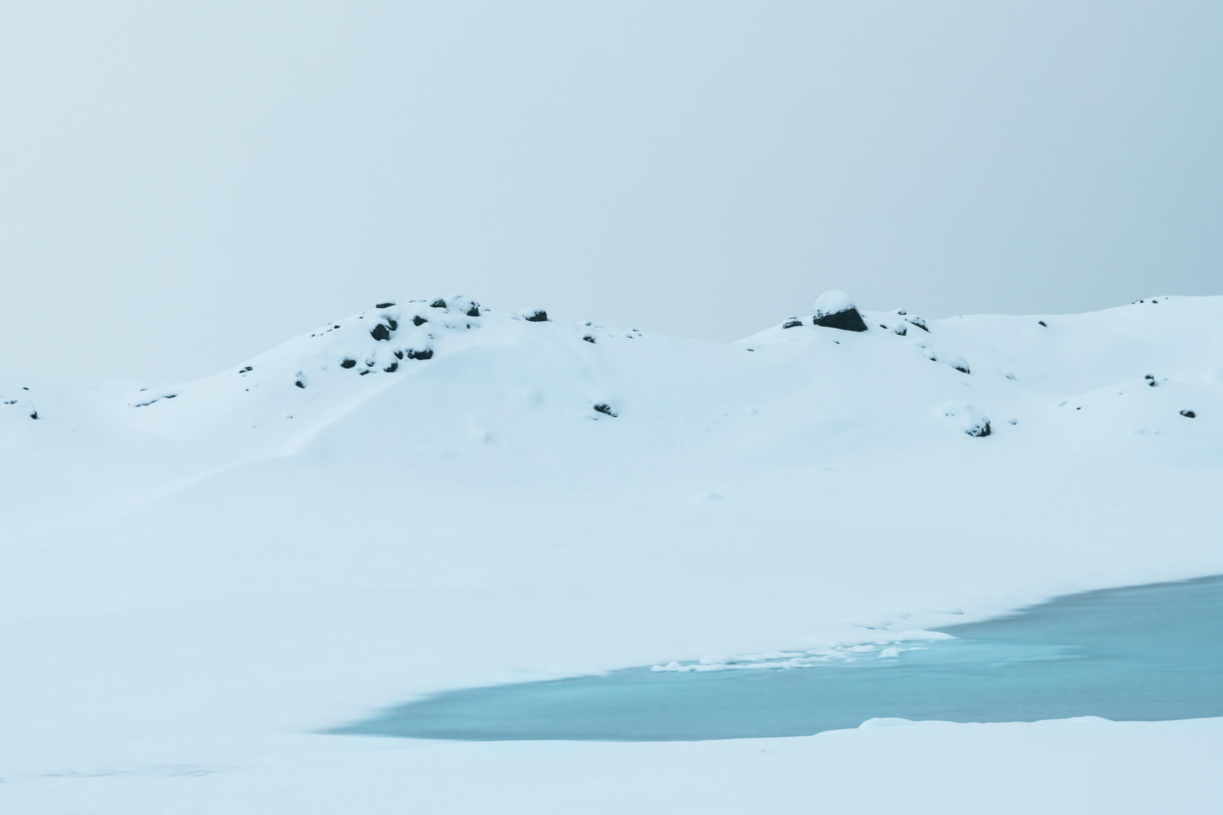 Minimalist winter landscape with rocks on a snowy hill in Iceland