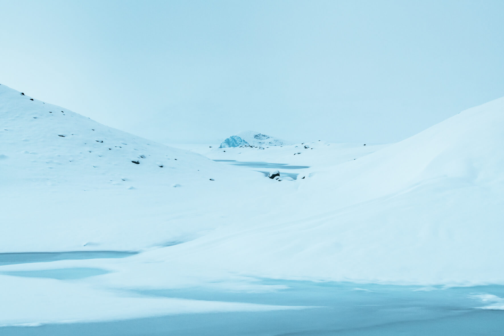 Snow covered iceberg in glacier lagoon Jökulsárlón between two hills