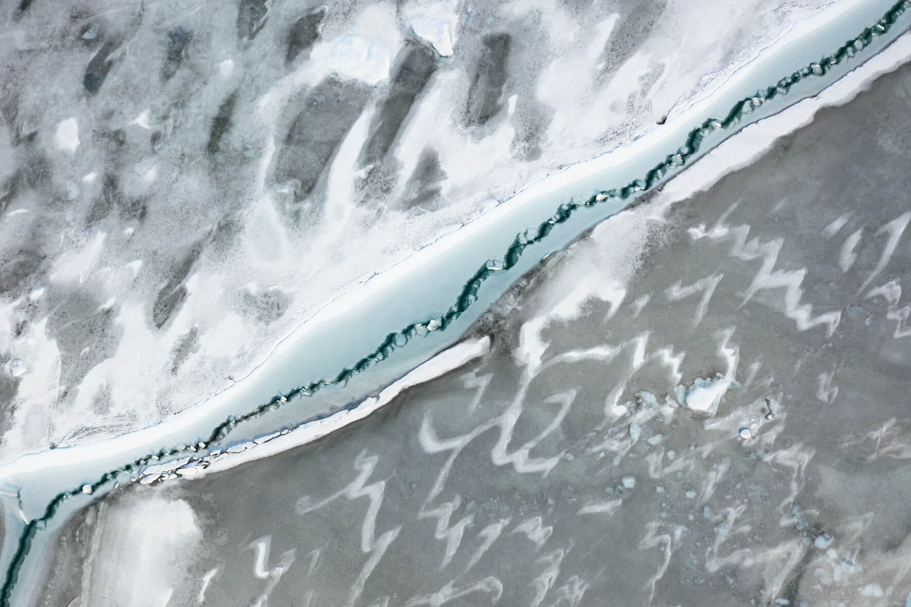 Aerial view of frozen lake Jökulsárlón in Iceland with abstract patterns on the surface and cracks in the ice