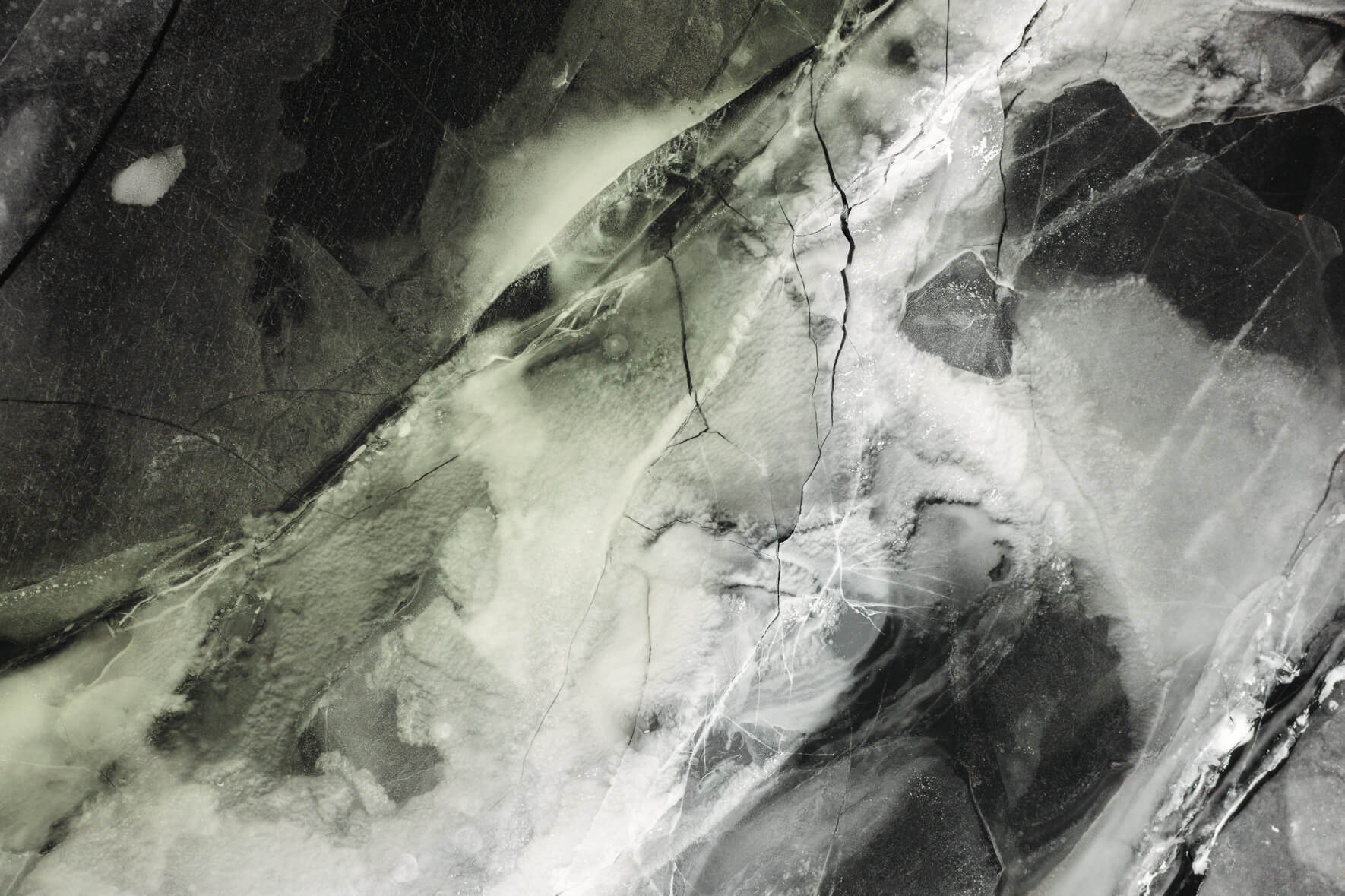 Frozen lake in Norway from an aerial perspective with colorful and abstract textures and cracks in the ice surface