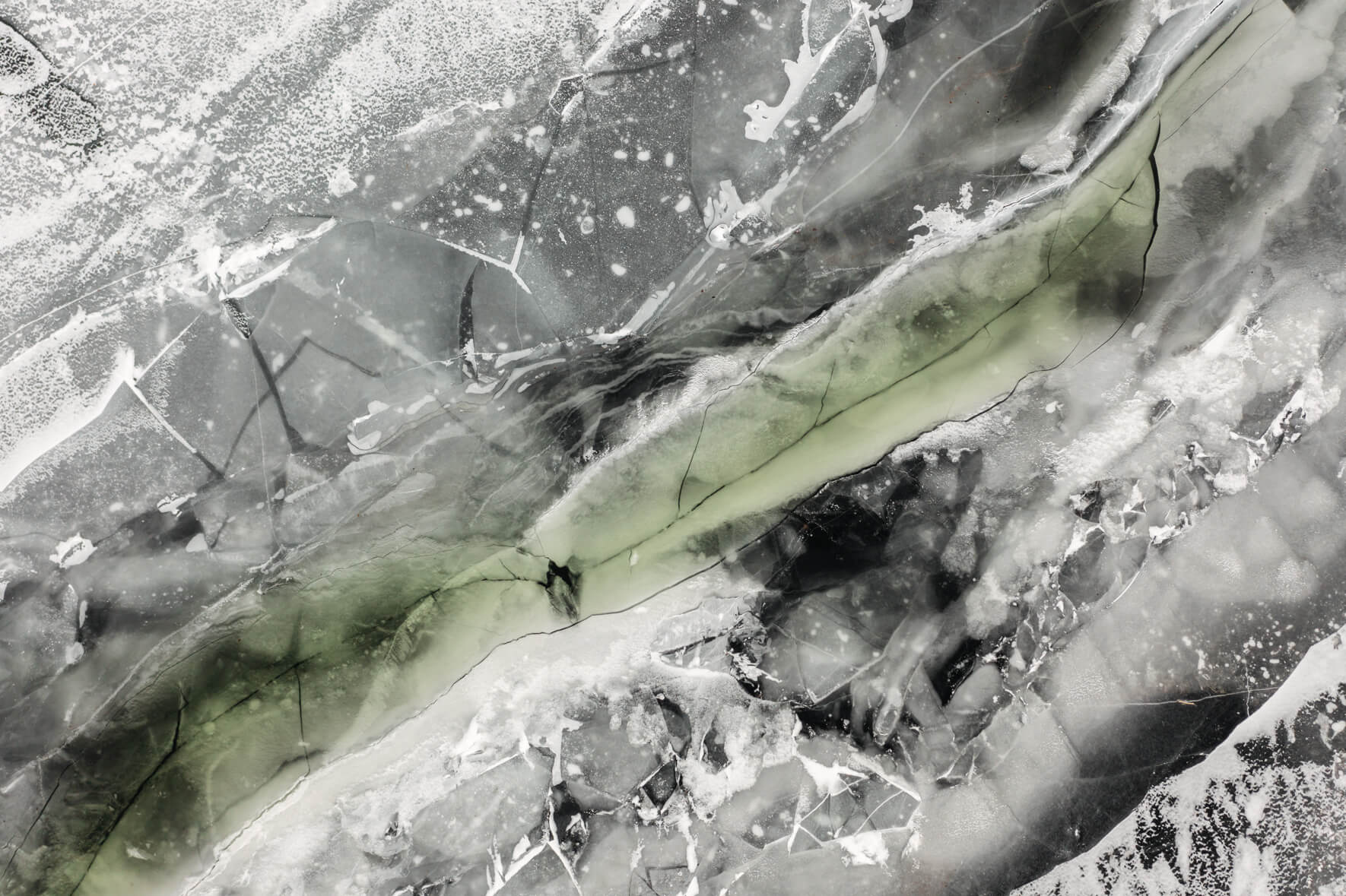 Frozen lake in Norway from an aerial view with cracks and water channels on the ice surface