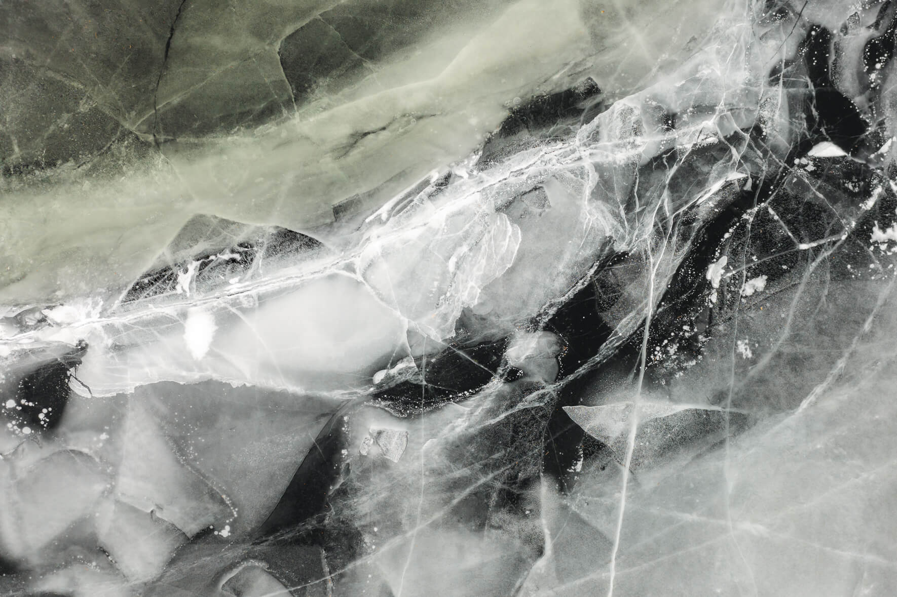 Aerial view of frozen lake with various cracks in the ice
