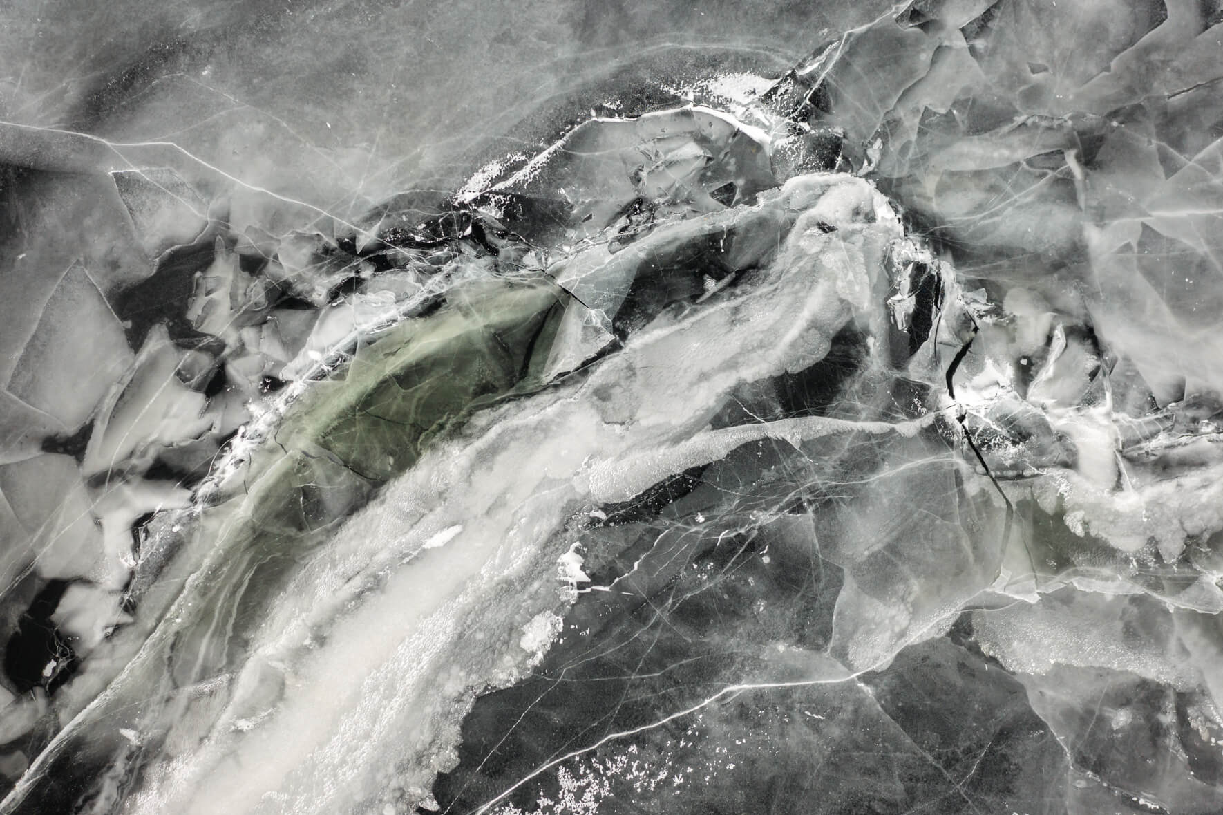 Aerial view of frozen lake Åraksfjorden with abstract textures and patterns and ice breaking apart