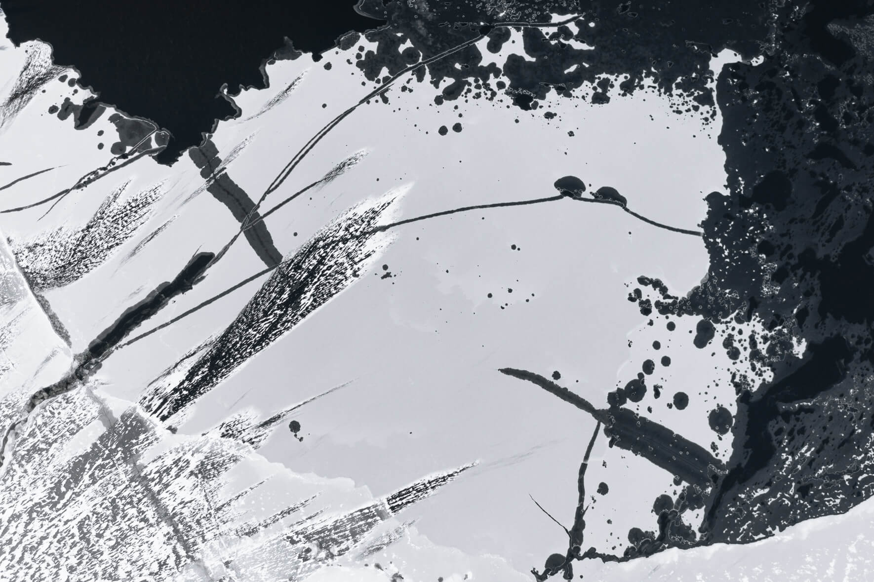 Aerial view of frozen lake with windblown snow and various holes in ice due to thaw