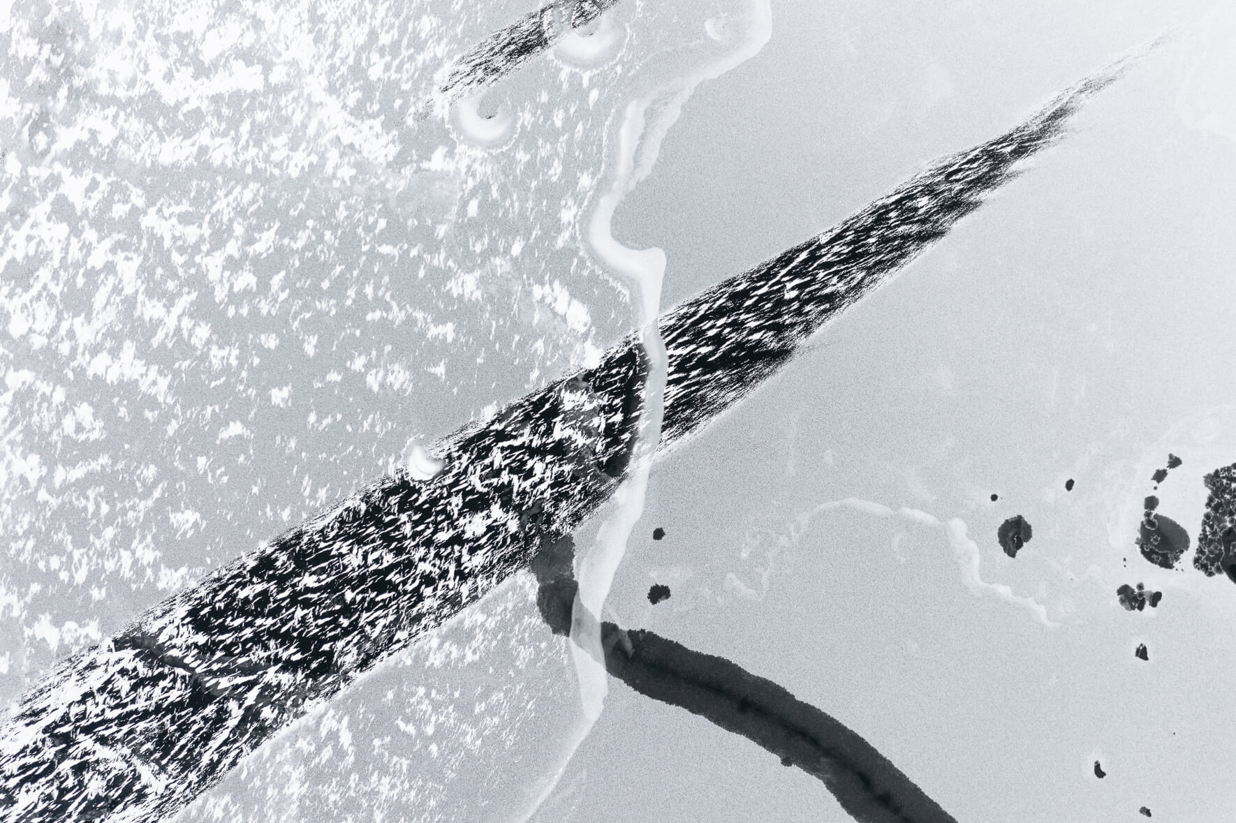 Frozen lake in Norway with windblown snow and holes in ice due to thaw