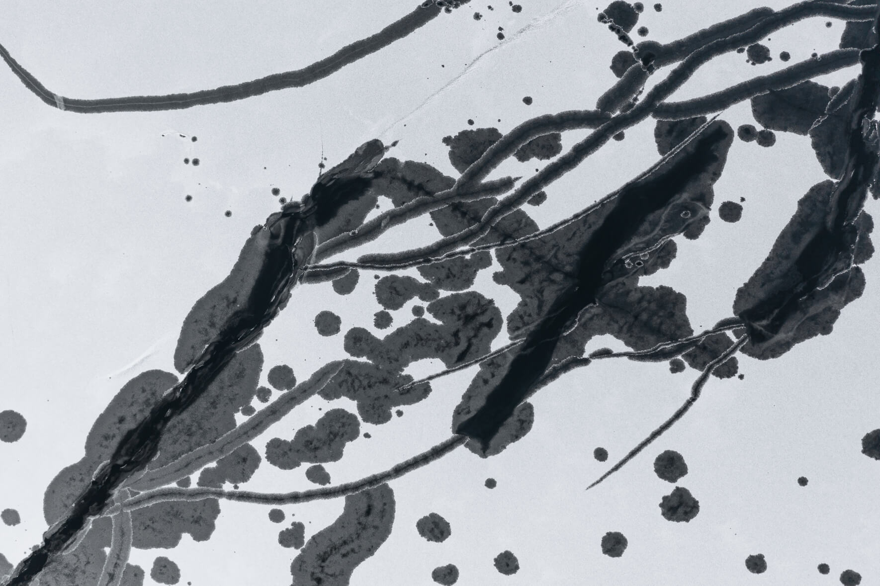 Aerial view of a frozen lake in Norway with large holes and cracks in ice due to thawing weather