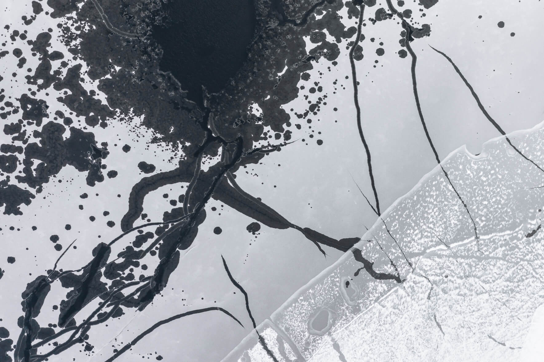 Aerial photograph of a frozen lake in Norway with cracks and open channels in the ice due to thawing weather