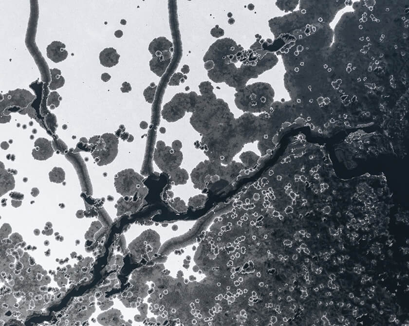 Aerial photograph of a frozen lake in Norway with cracks and open channels in the ice due to thawing weather