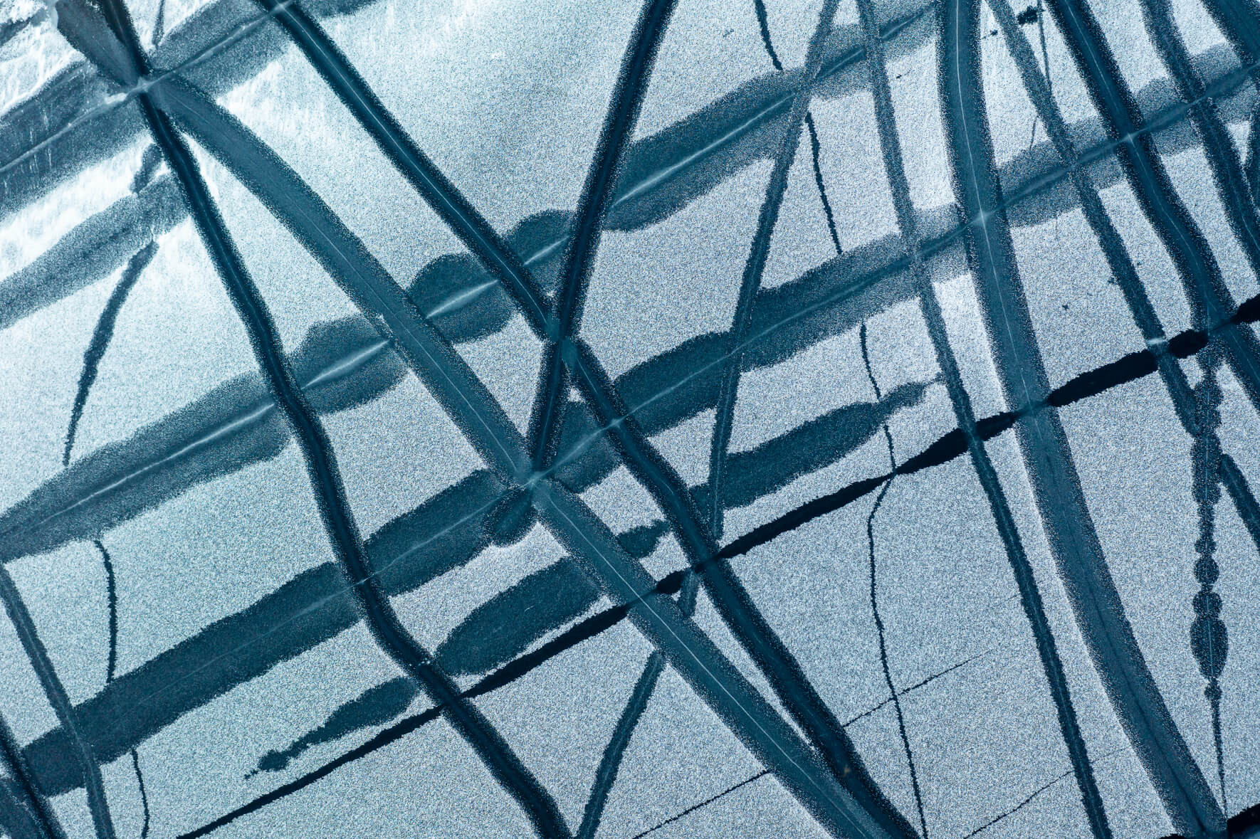 Aerial view of a frozen lake in Norway with a maze of cracks and channels caused by warm temperatures