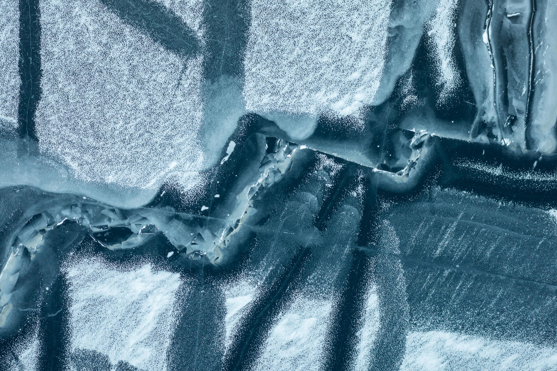 Aerial view of a frozen lake in Norway with a maze of cracks caused by warmer temperatures