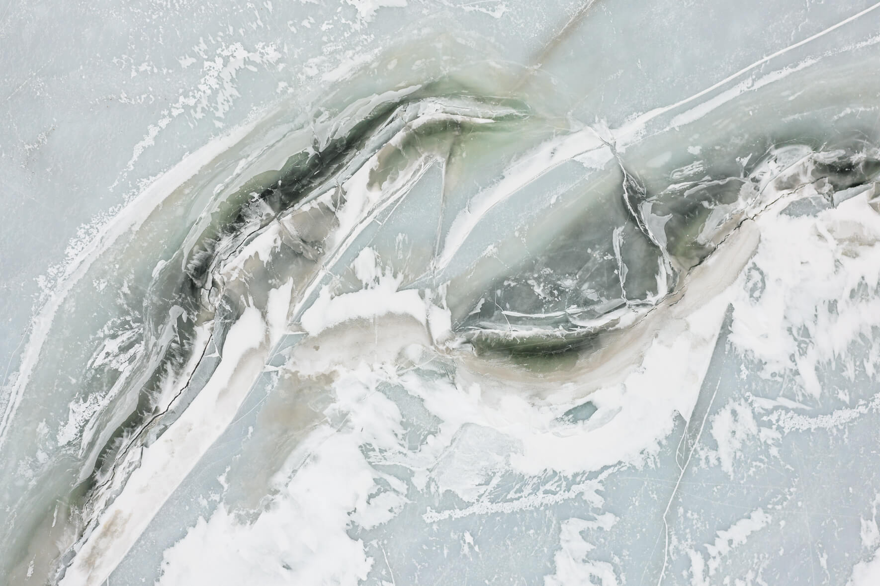 Aerial view of a frozen lake in Norway with cracks in the snow covered surface