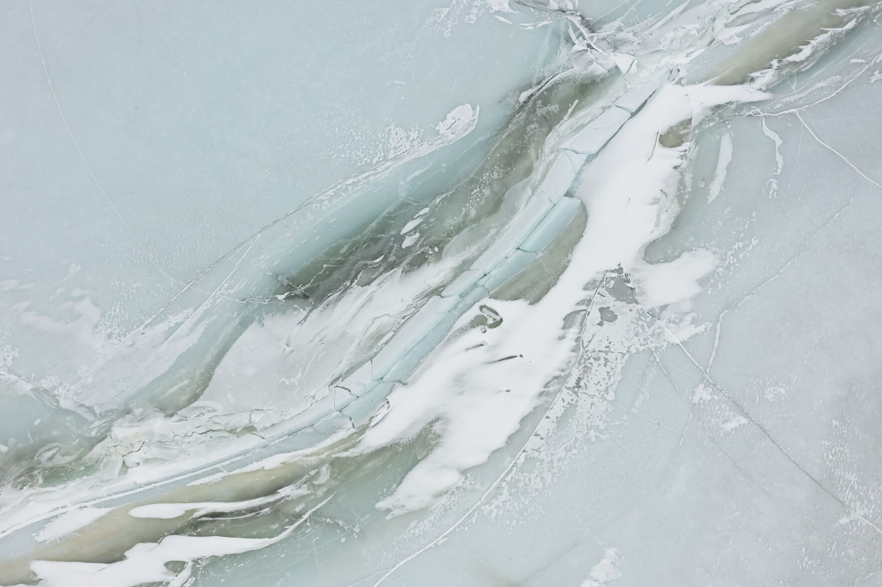 A frozen lake in Norway seen from above with massive cracks and faults in the ice
