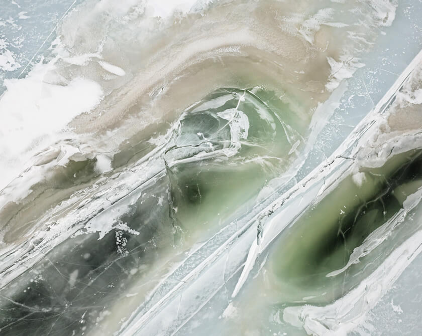 Aerial view of frozen lake Åraksfjorden in Norway with cracks in the ice surface