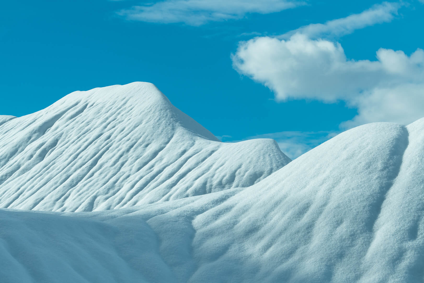 Abstract landscape with snow covered hills in a quarry and a blue sky with clouds